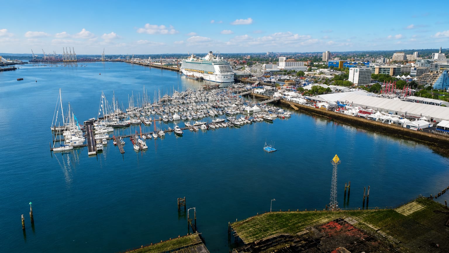 Southampton's waterfront with a moored cruise ship, yacht marina and dockside buildings under a blue sky