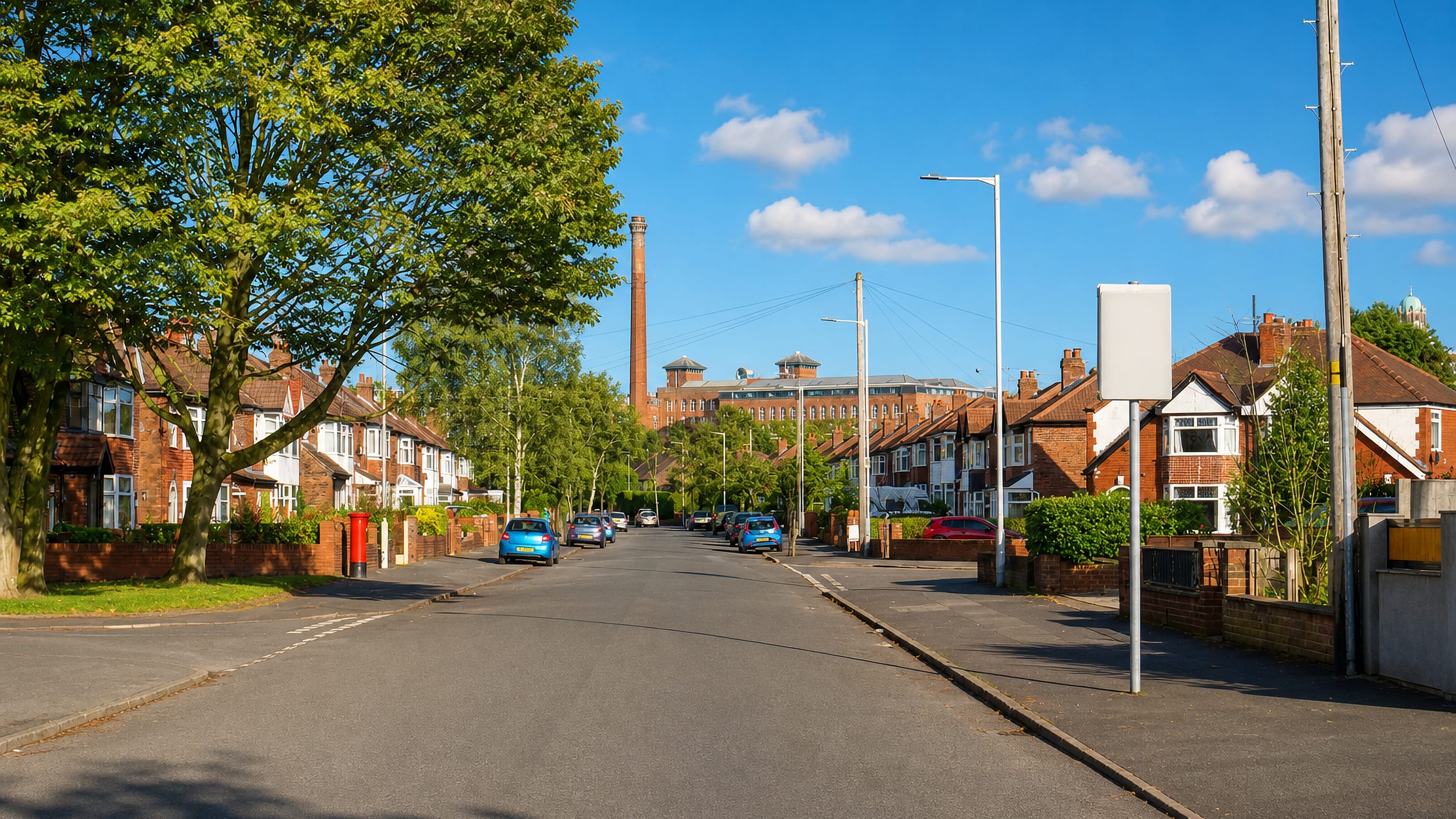 Tree-lined street of red-brick semis in Heaton Chapel, Stockport, with a former mill chimney on the skyline