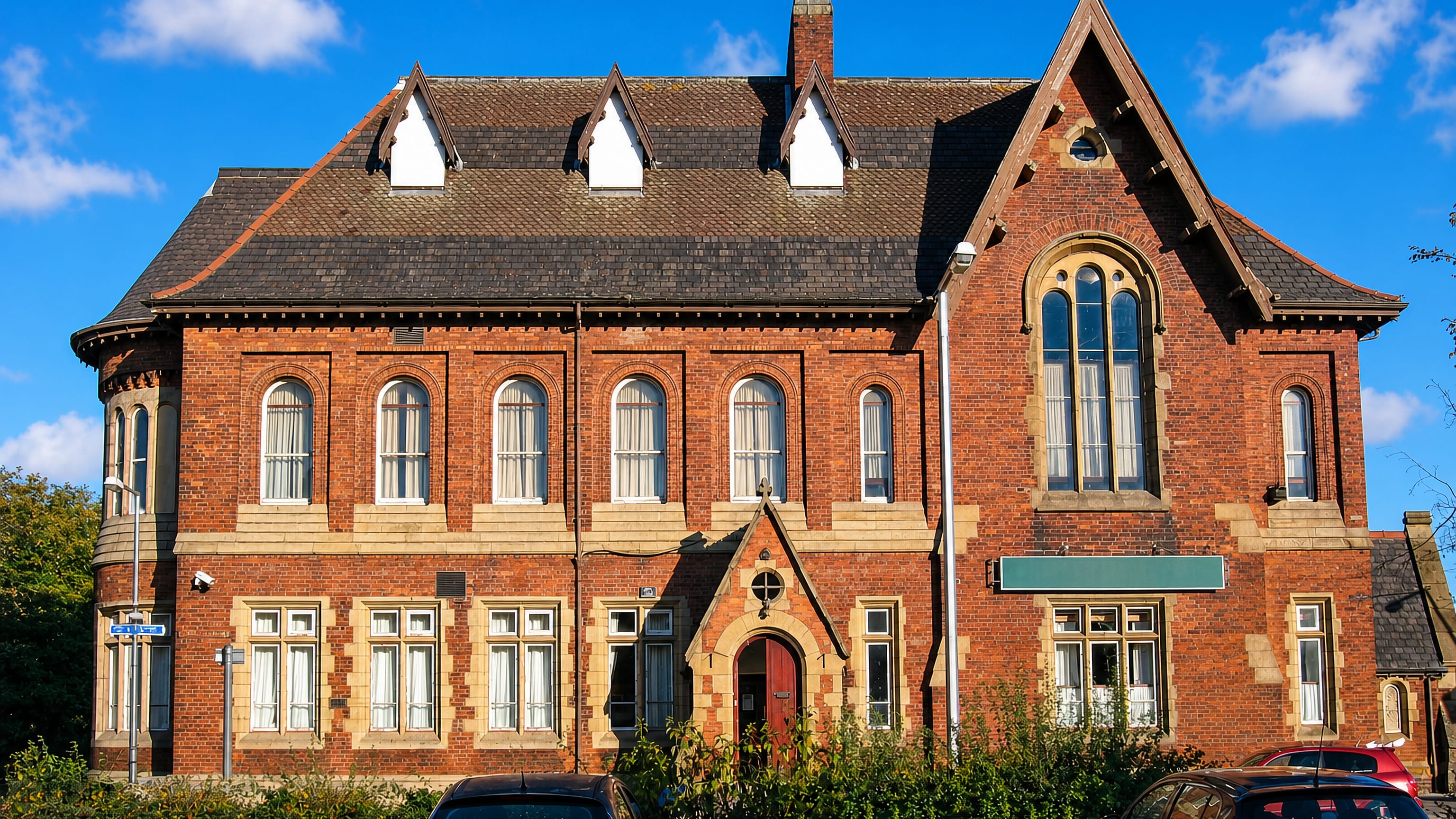 Victorian red-brick institute building with gabled roofline on a sunny street in Reddish, Stockport.