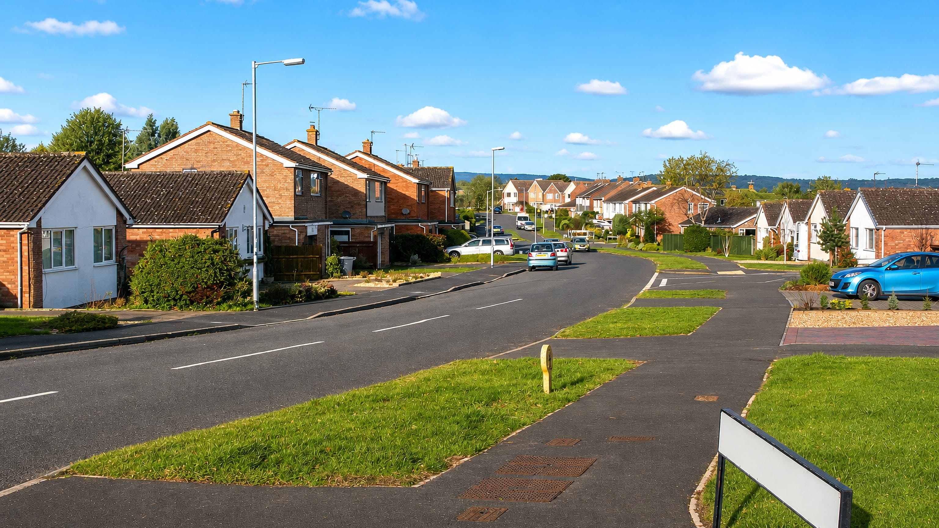 Quiet suburban street of brick houses with grass verges in Comeytrowe on the edge of Taunton, Somerset.