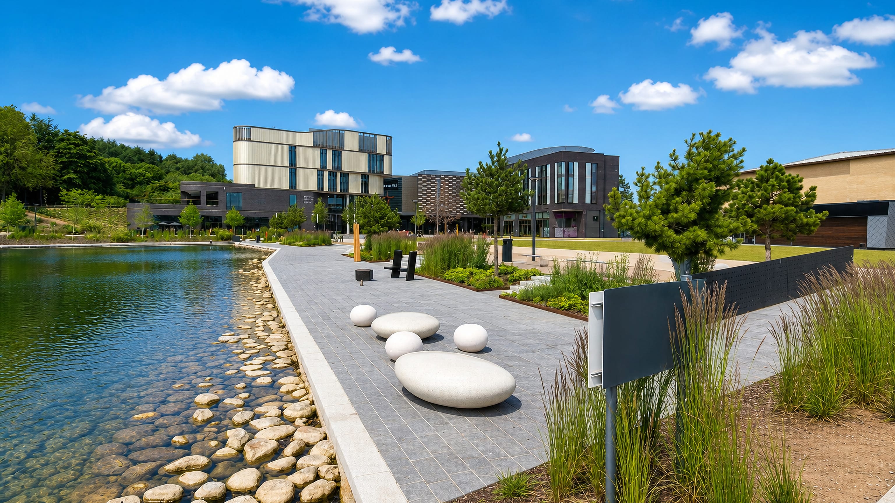 Modern town-centre buildings and a landscaped lakeside walkway with boulder seats in Telford, Shropshire.