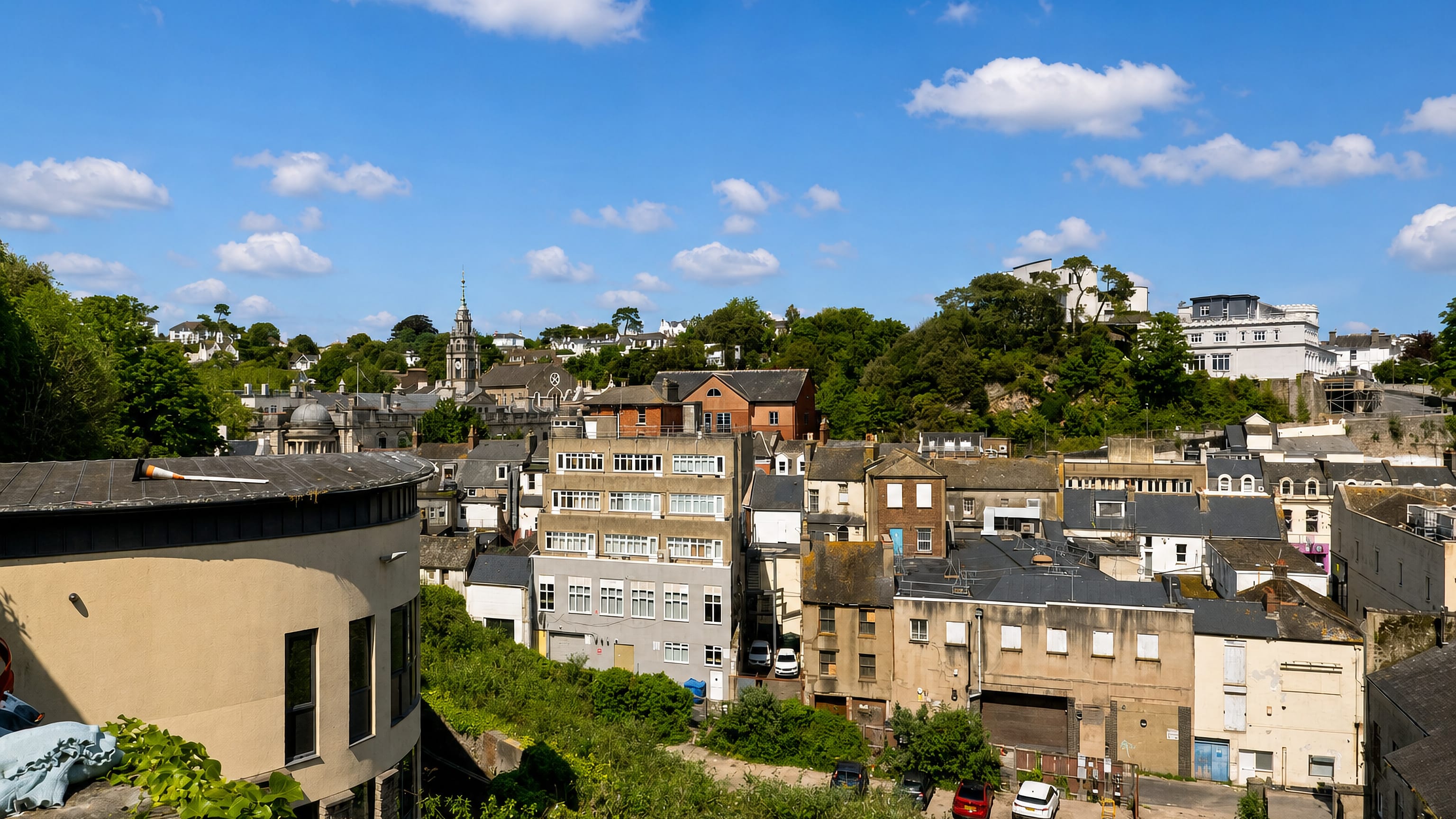 Terraced houses and a church spire climbing the wooded hillside of Ellacombe in Torquay, Devon.