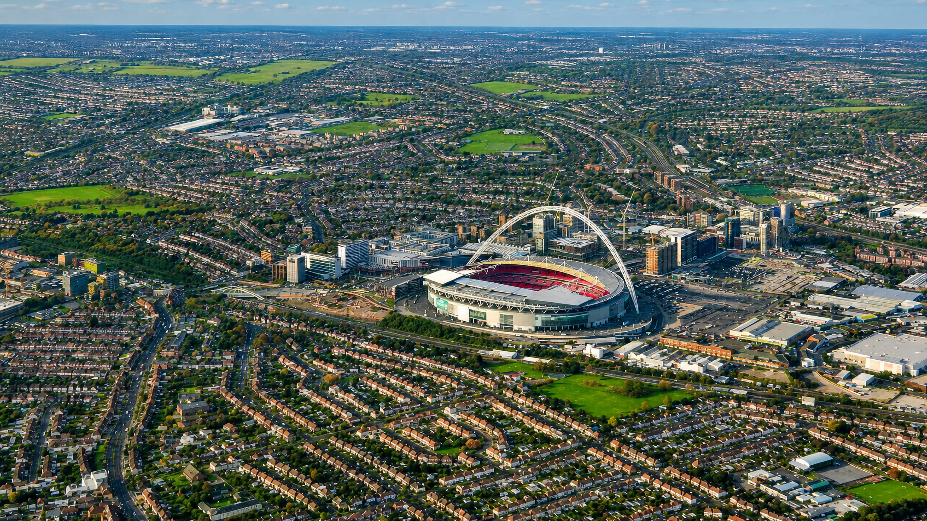 Aerial view of Wembley Stadium's arch rising over the terraced streets and suburbs of Wembley, London