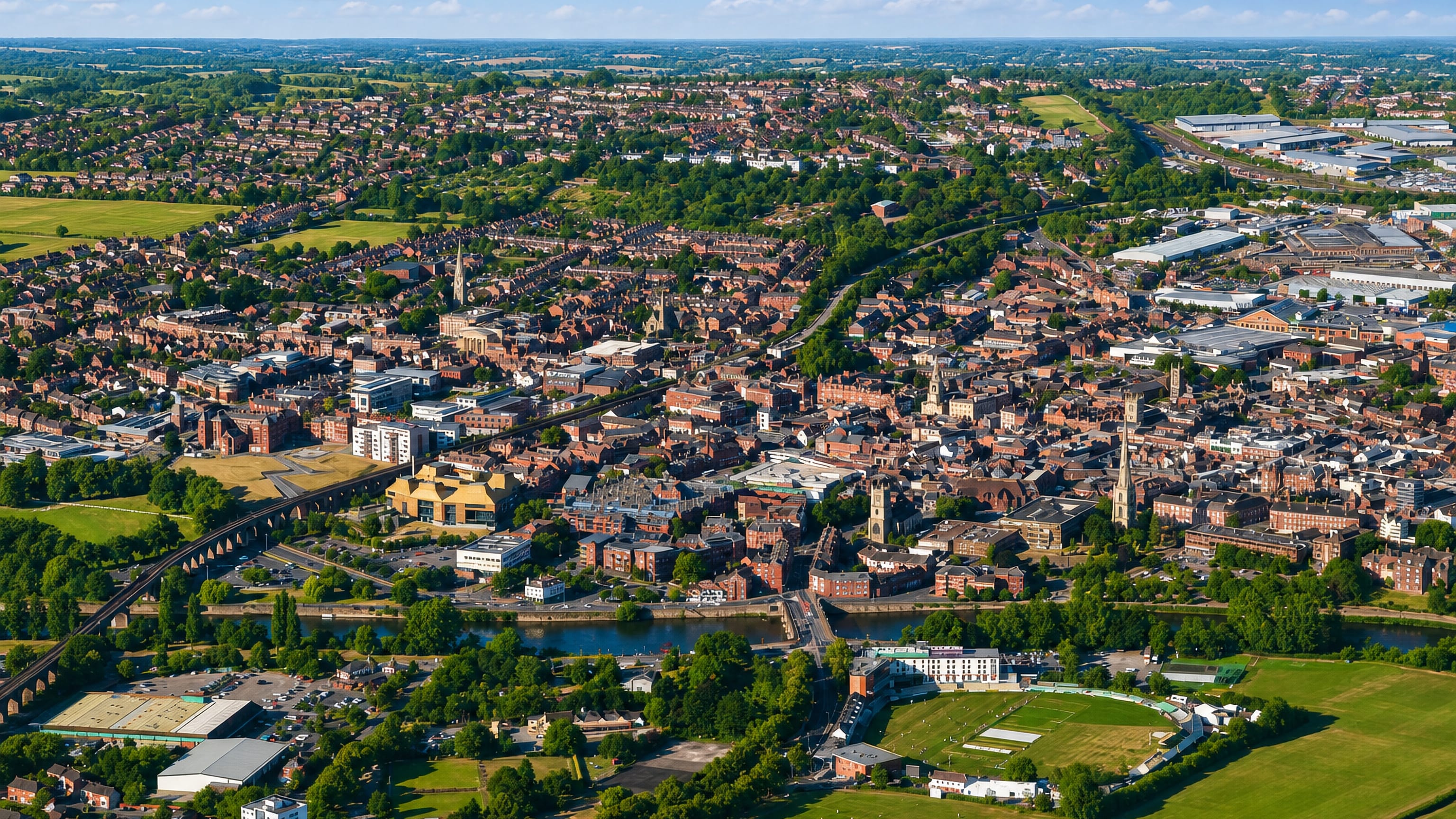 Aerial view of Worcester, England, with red-brick streets, the River Severn and the riverside county cricket ground.