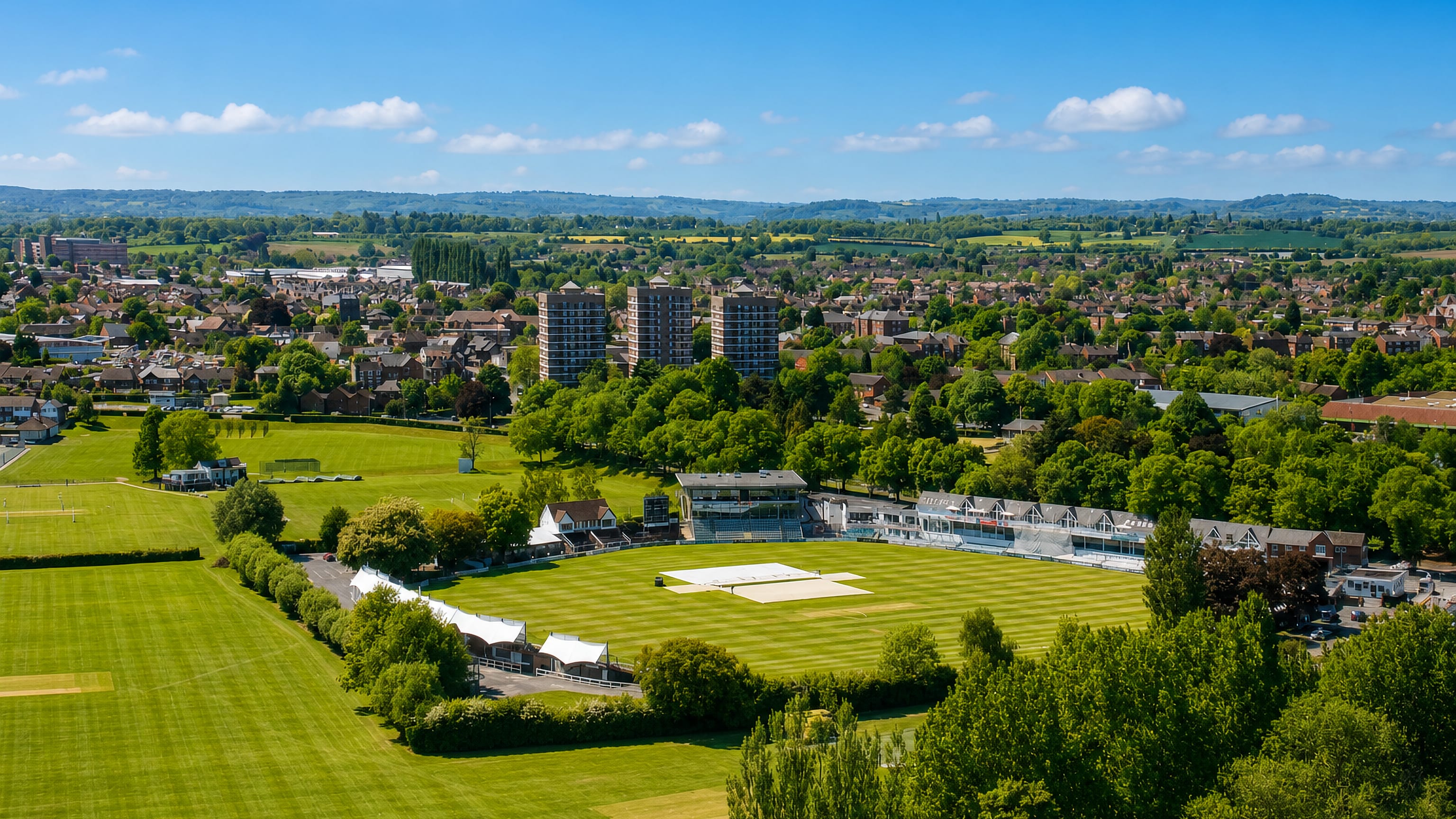 Cricket ground and pavilion among the rooftops and tower blocks of St John's, Worcester.