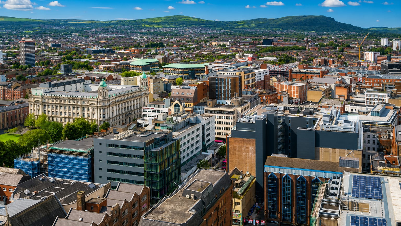 Aerial view over Belfast city centre with the domed City Hall and green hills rising behind