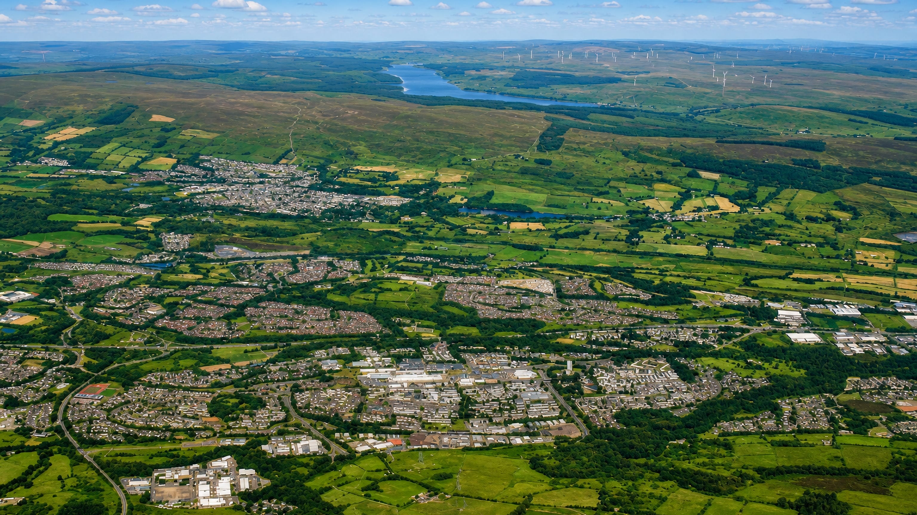Aerial view of Abronhill and Cumbernauld's housing estates ringed by farmland, moorland and wind turbines.