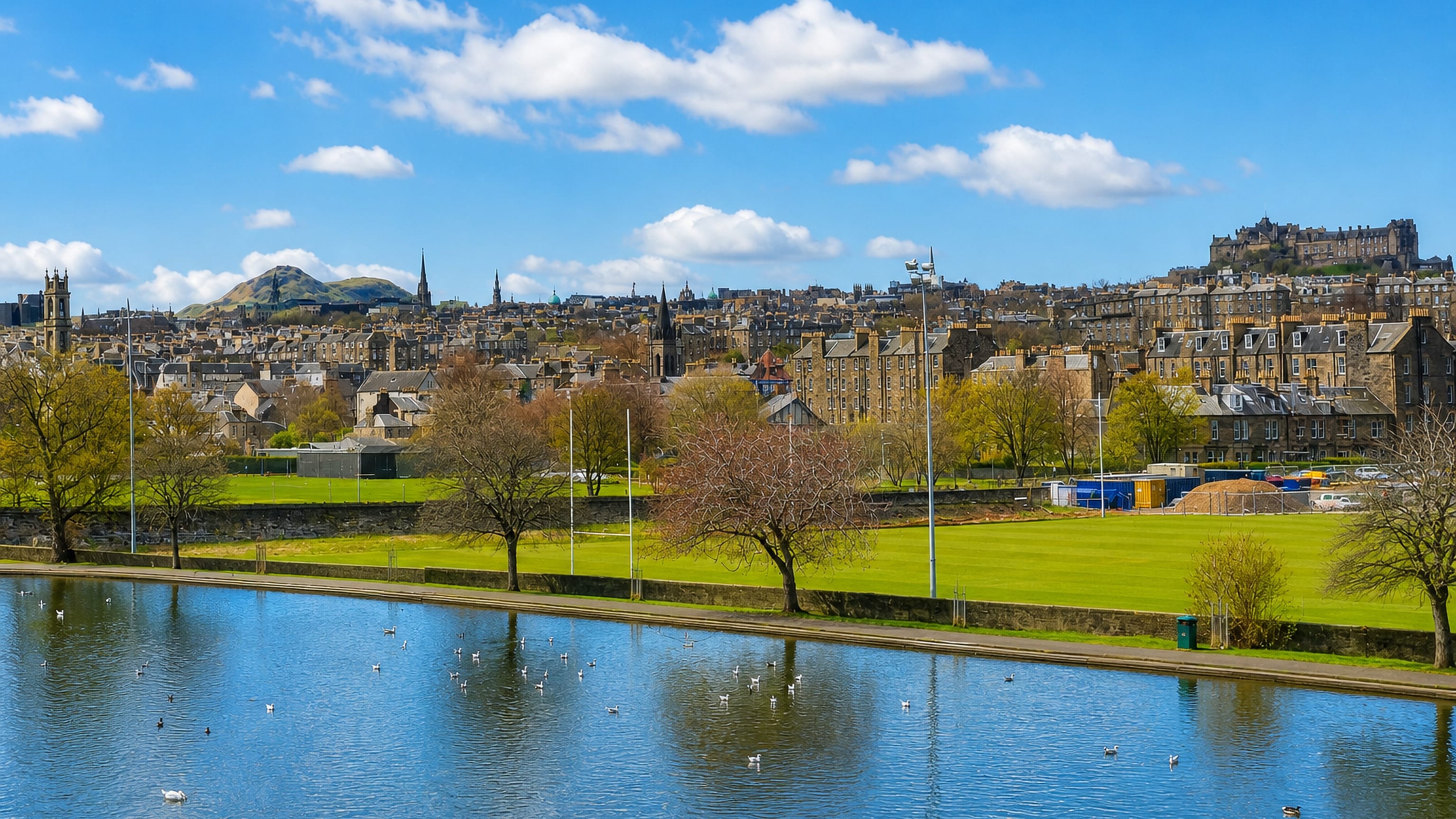 Edinburgh Castle and Arthur's Seat on the skyline beyond the pond and playing fields of Inverleith Park