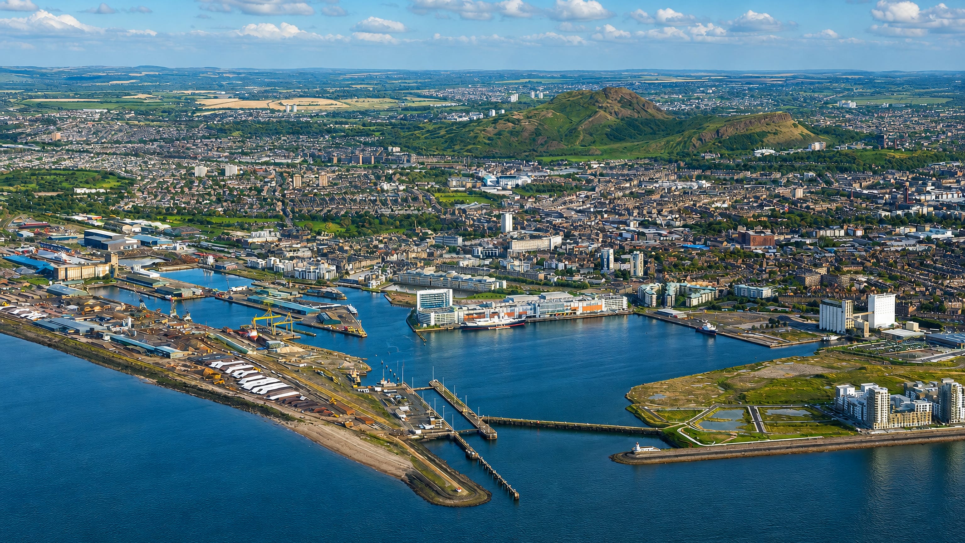 Aerial view of Leith's docks and Ocean Terminal with Edinburgh and Arthur's Seat rising behind.