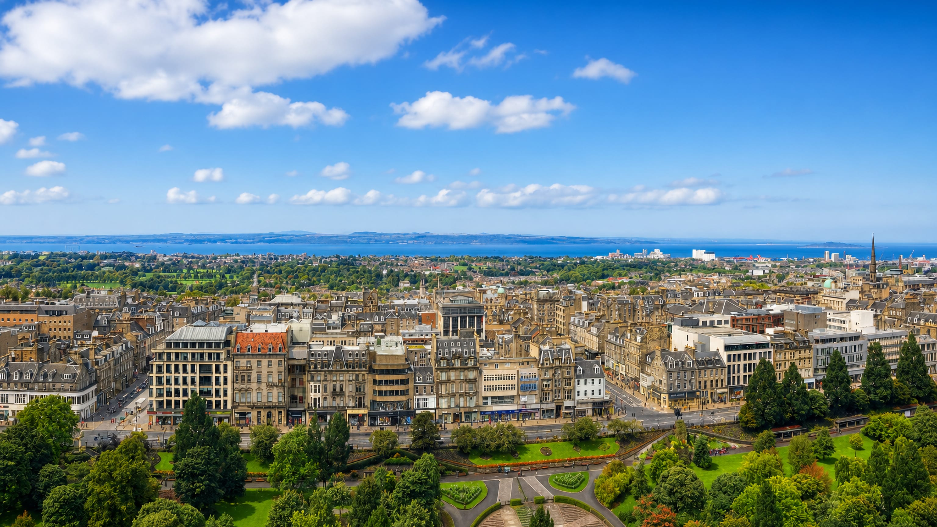 Edinburgh's New Town rooftops seen across Princes Street Gardens toward the Firth of Forth.