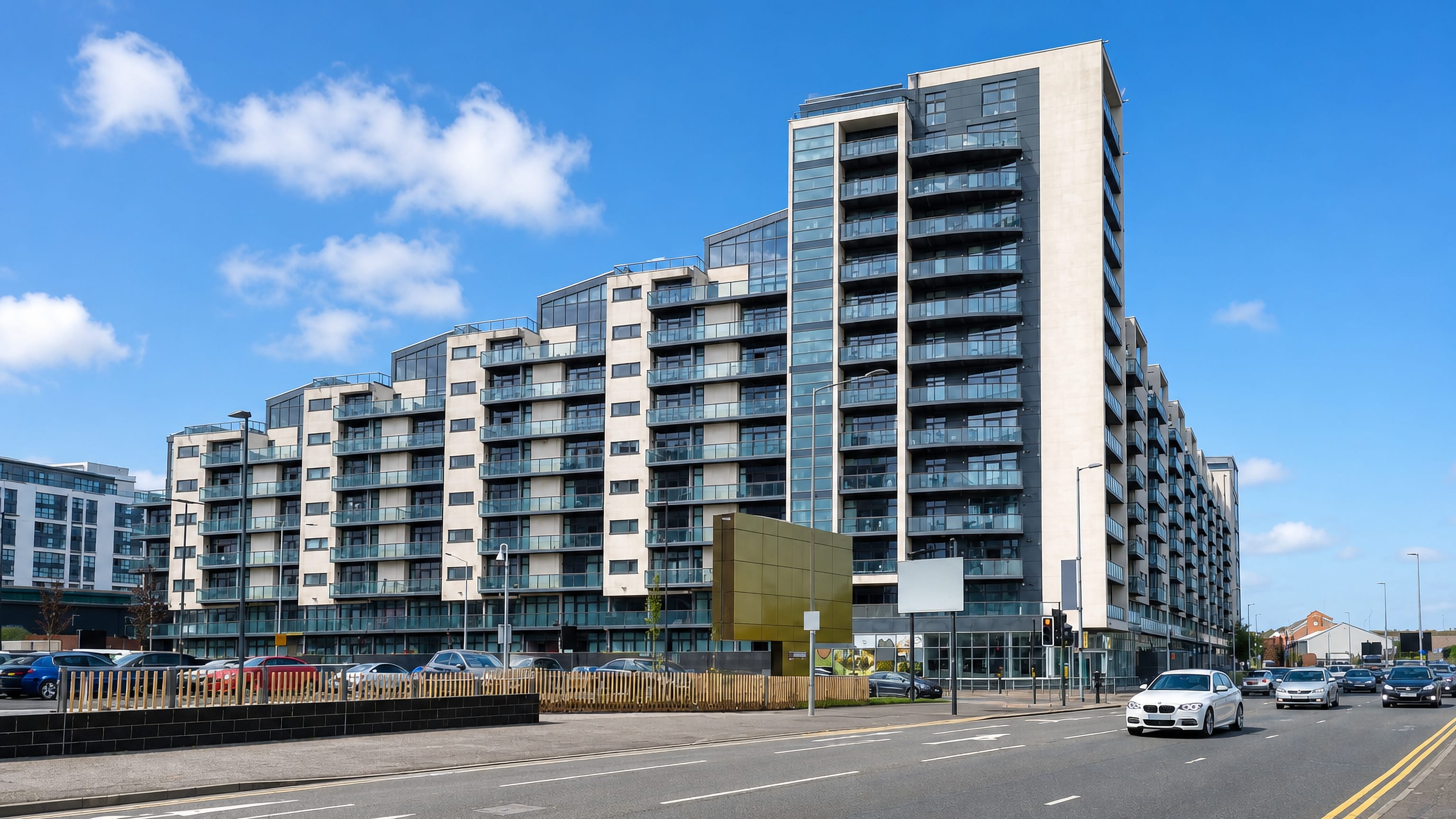 Stepped riverside apartment blocks lining a wide road in Finnieston, Glasgow, under a bright sky