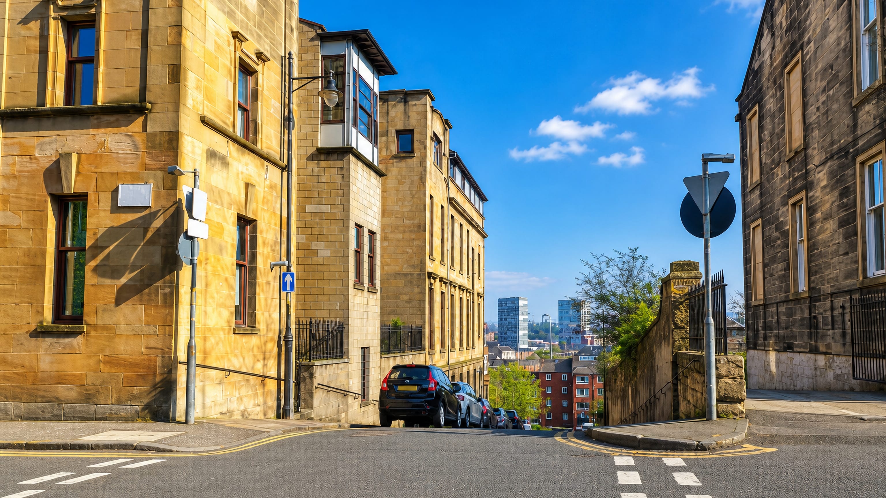 Steep sandstone tenement street in Garnethill, Glasgow, looking down to the city centre skyline