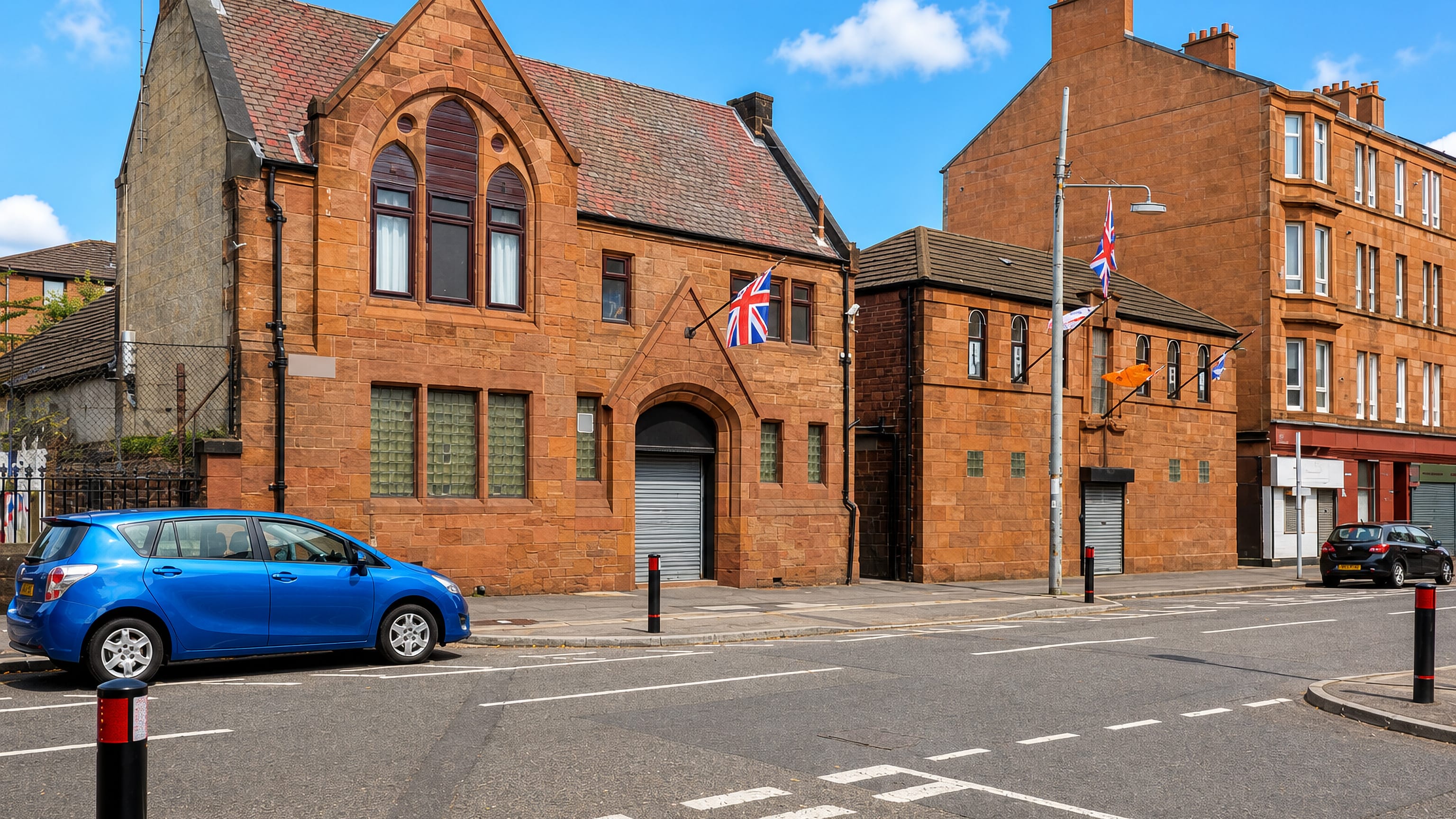 Red sandstone Victorian hall and tenements on a sunlit street corner in Kinning Park, Glasgow.