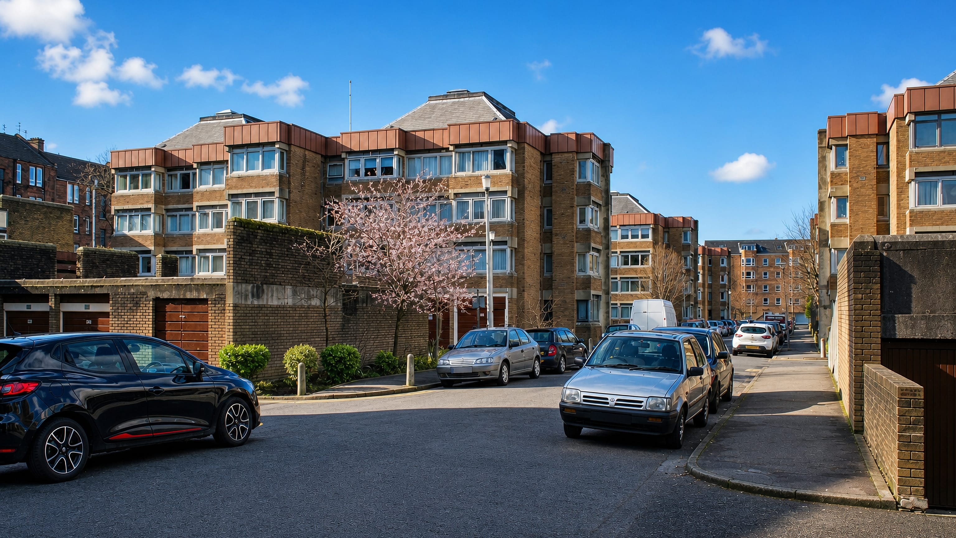 Brick low-rise flats and parked cars on a sunlit residential street in Langside, southside Glasgow.