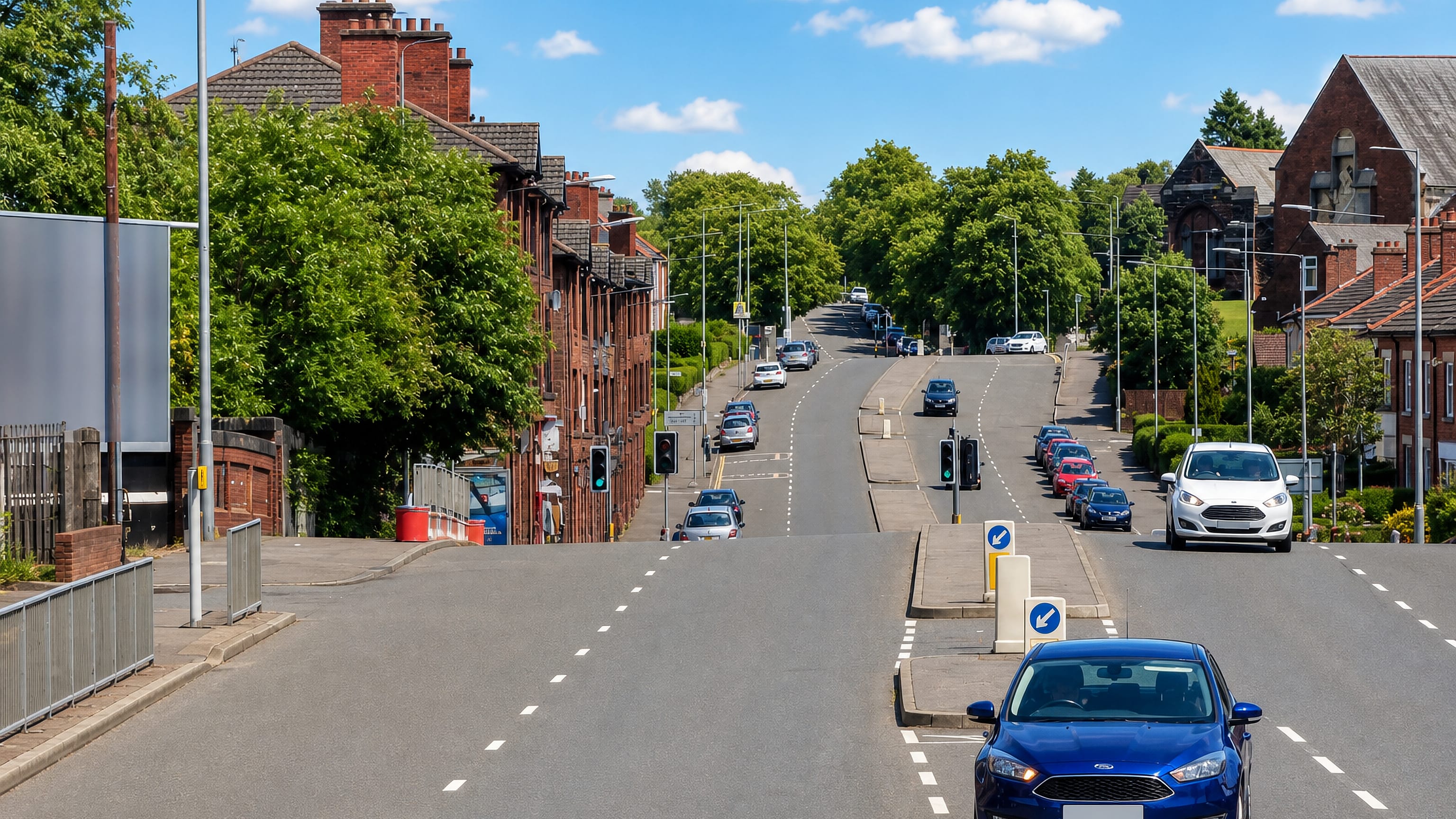 Traffic on the dual carriageway past red-brick tenements and terraces in Riddrie, Glasgow.
