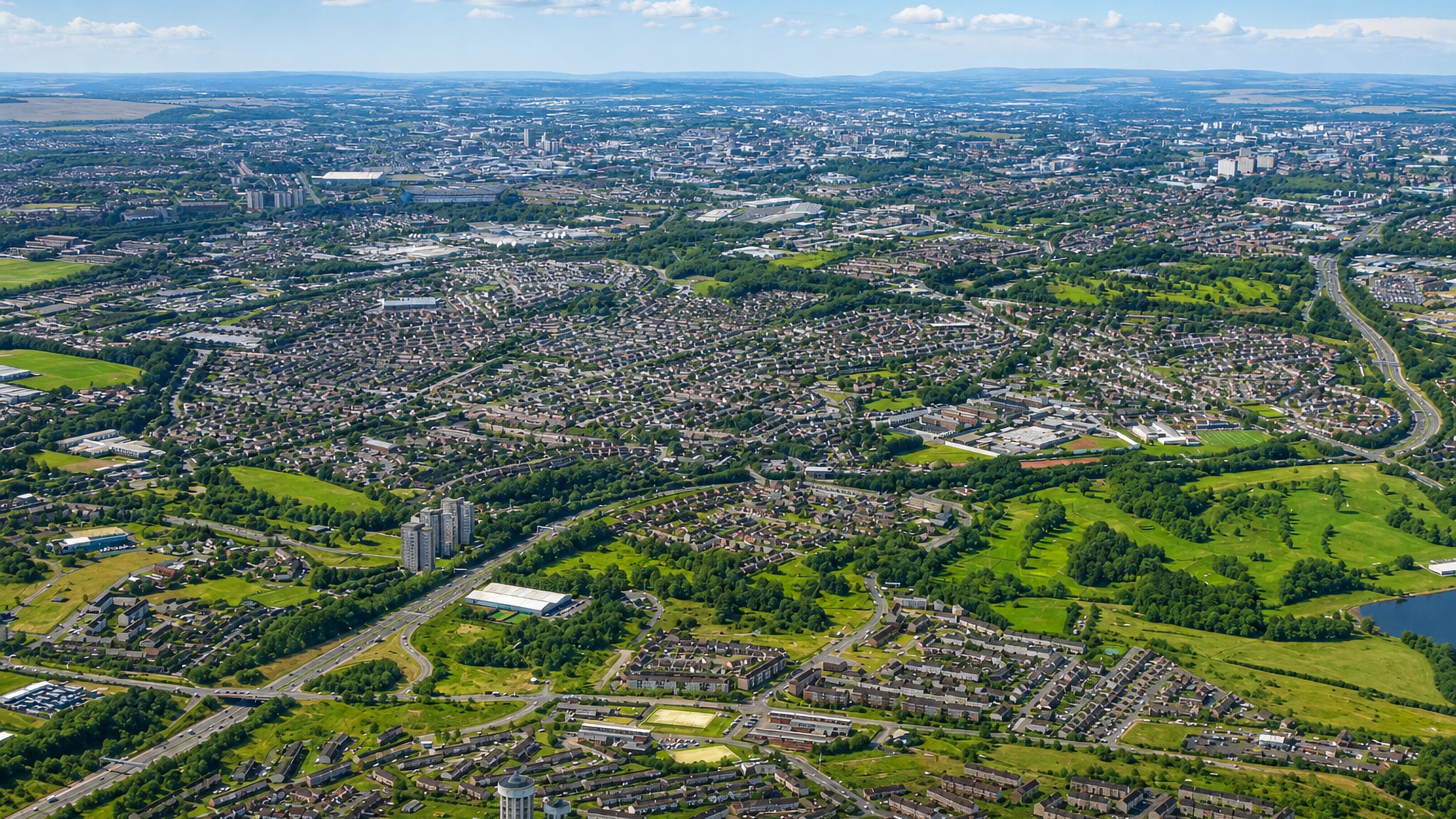Aerial view over housing estates and green space toward the Glasgow city skyline from Ruchazie.