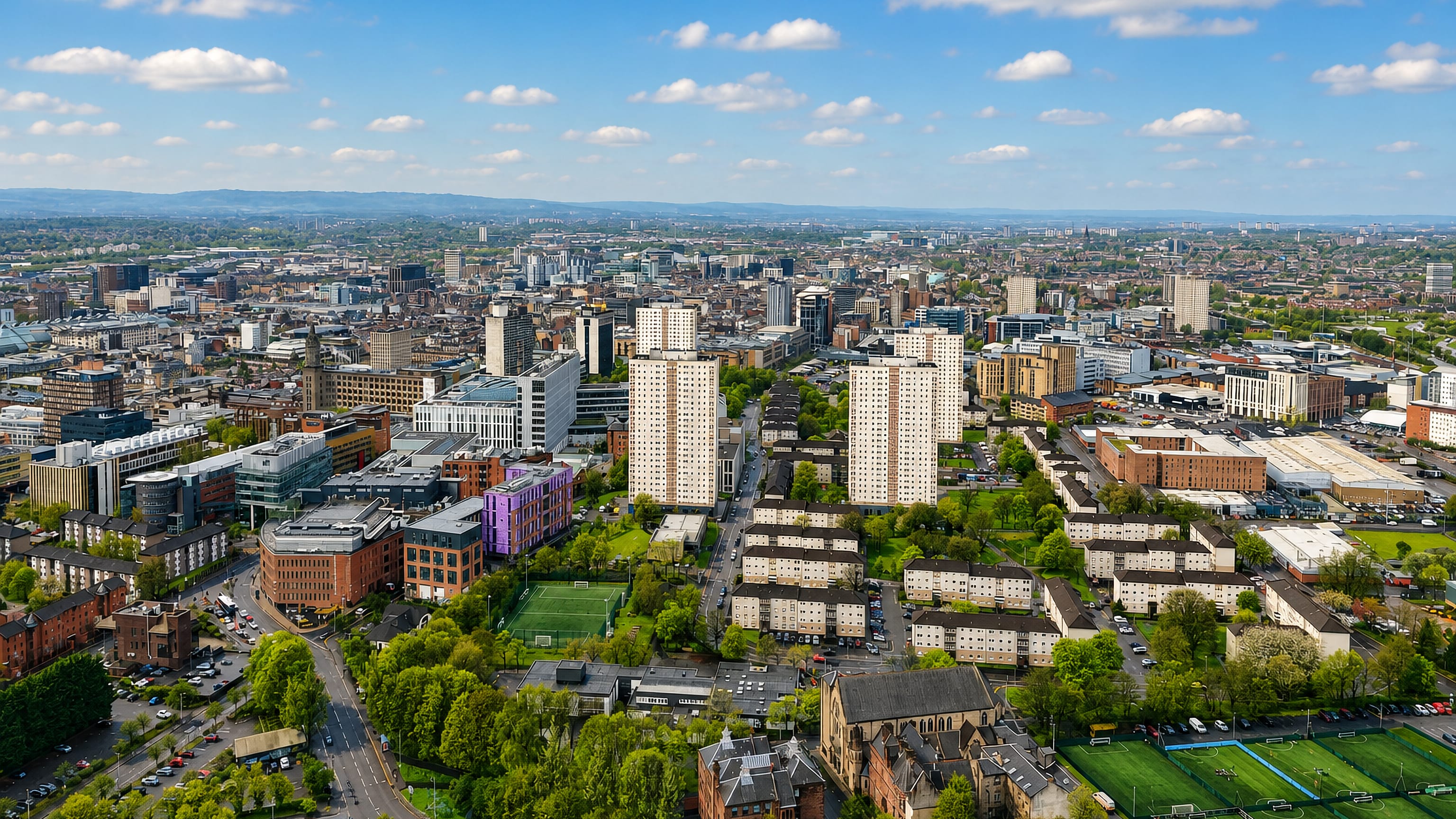 Aerial view of Townhead in Glasgow, with tower blocks, tenement rows, a church and the city skyline beyond.