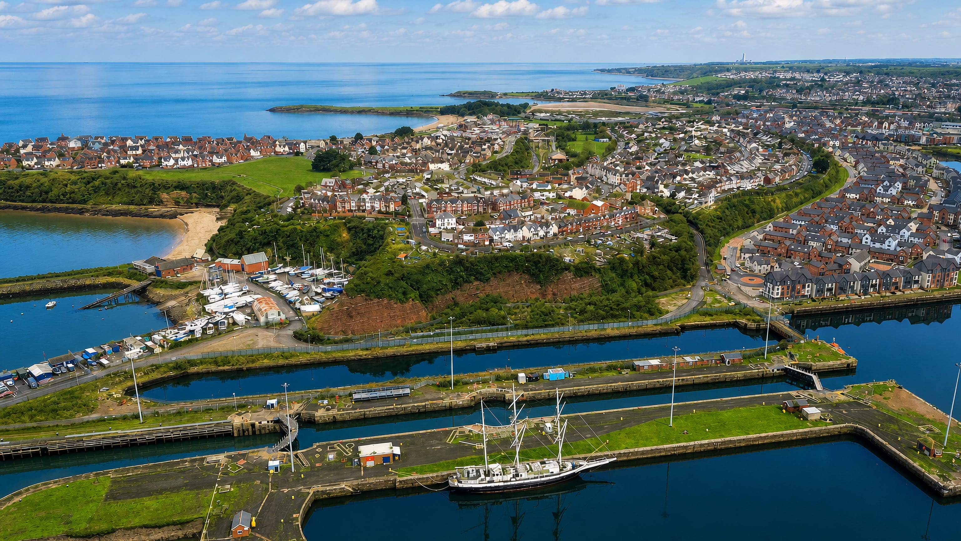 Aerial view of Barry Dock's locks and basins with the seaside town and beach beyond, Wales.