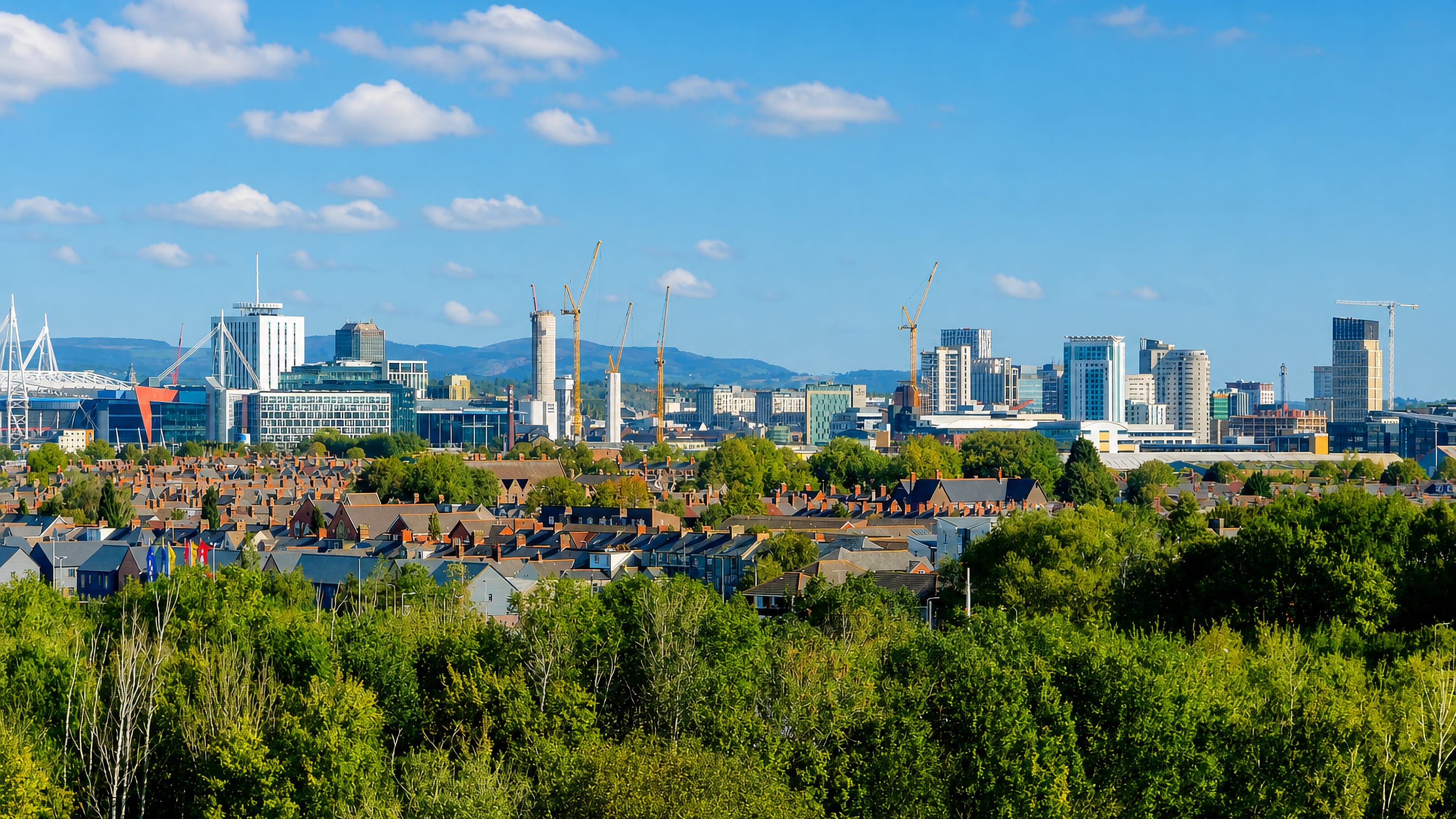 Cardiff skyline with the Principality Stadium arch, Wales Millennium Centre, and city towers rising beyond leafy terraced rooftops.