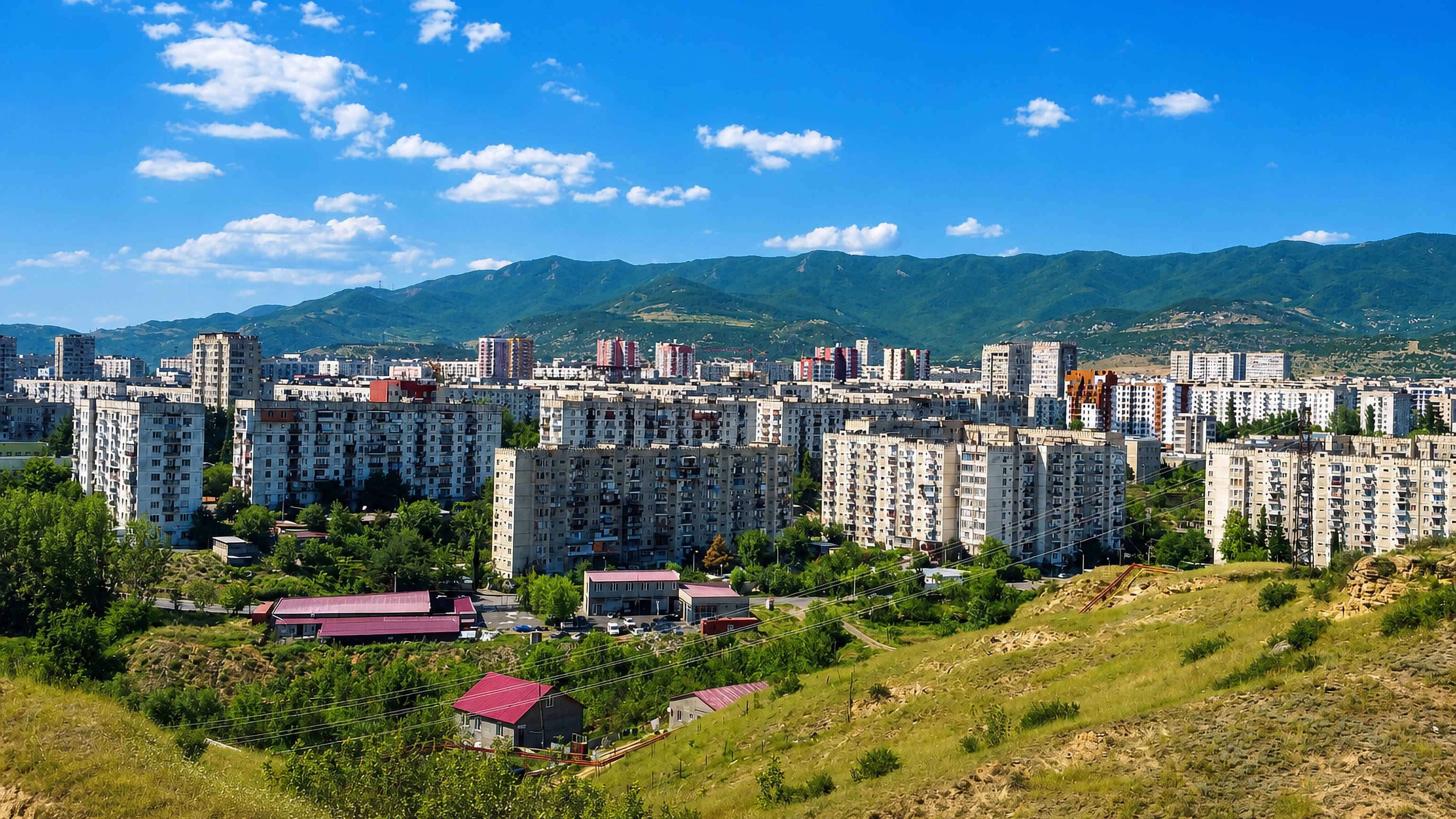 Rows of Soviet-era apartment blocks below green mountains in Gldani District, northern Tbilisi.