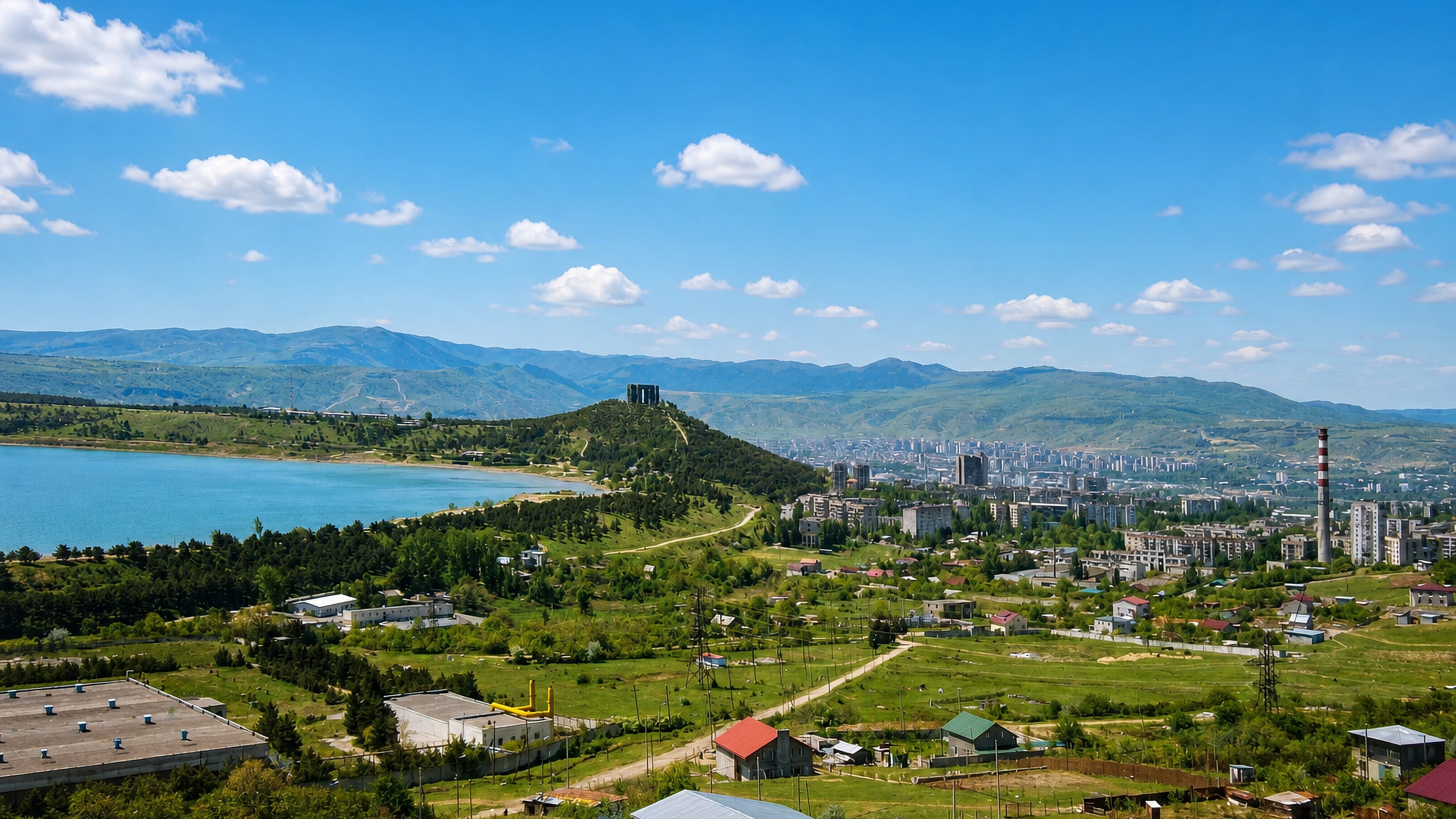 Hillside view over Nadzaladevi in northern Tbilisi with Soviet-era apartment blocks, a reservoir and hills