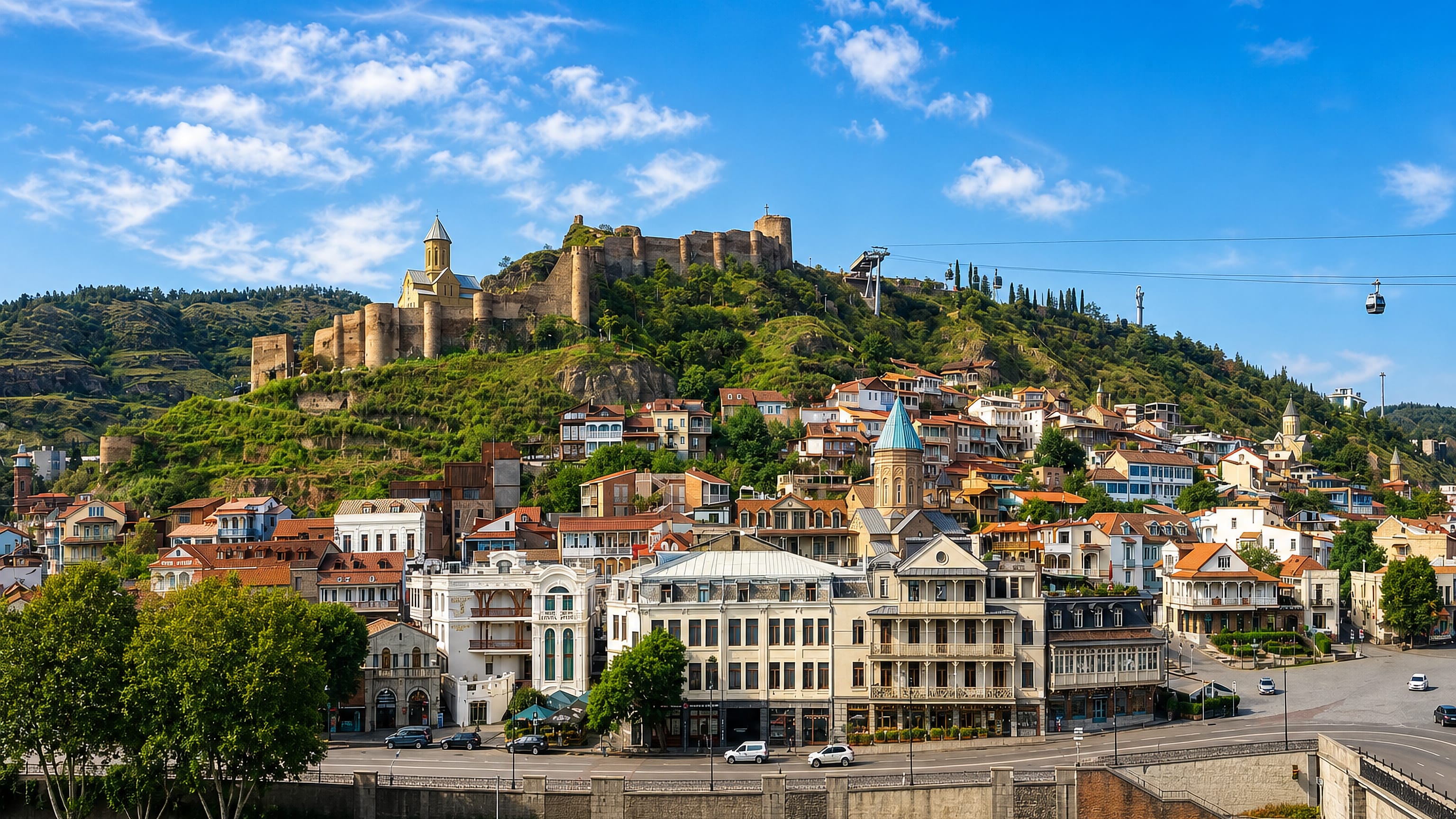 Old Tbilisi's balconied houses rising to Narikala Fortress, with the cable car and Kura embankment below