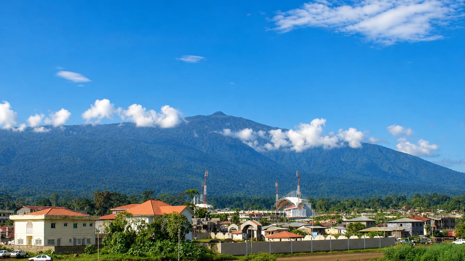 Malabo's low-rise buildings and a white modern mosque at the forested foot of the towering Pico Basile volcano