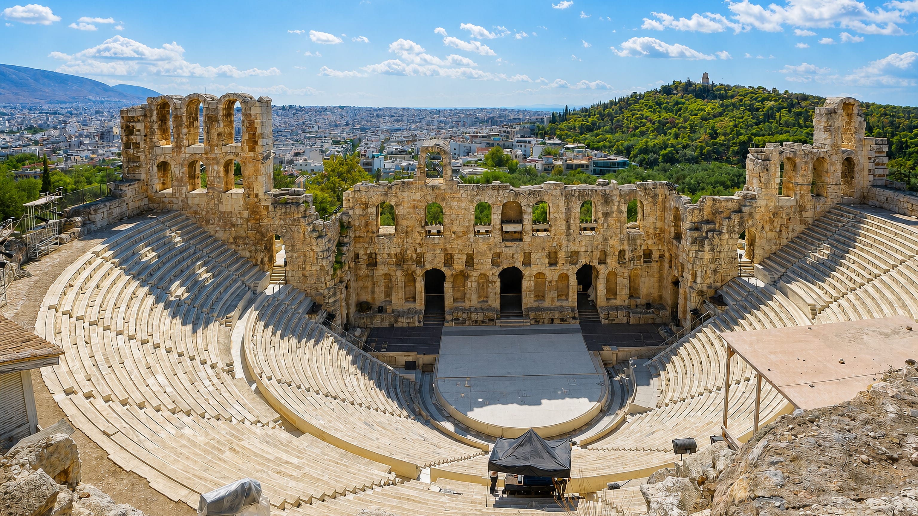 The Odeon of Herodes Atticus below the Acropolis, with Filopappou Hill and Athens rooftops beyond Thiseio.
