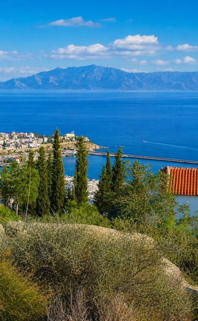 Kavala's old-town headland and fortress above the harbour, with the Aegean and distant mountains.