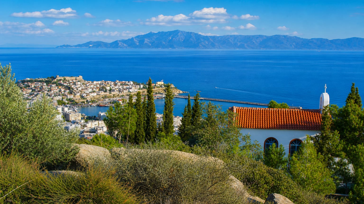 Kavala's old-town headland and fortress above the harbour, with the Aegean and distant mountains.