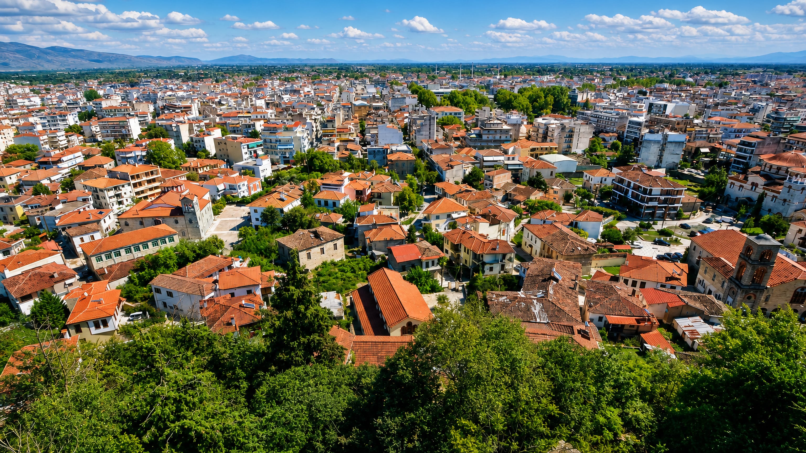 Red-tiled rooftops of Trikala below the castle hill, with the Thessalian plain and mountains beyond.