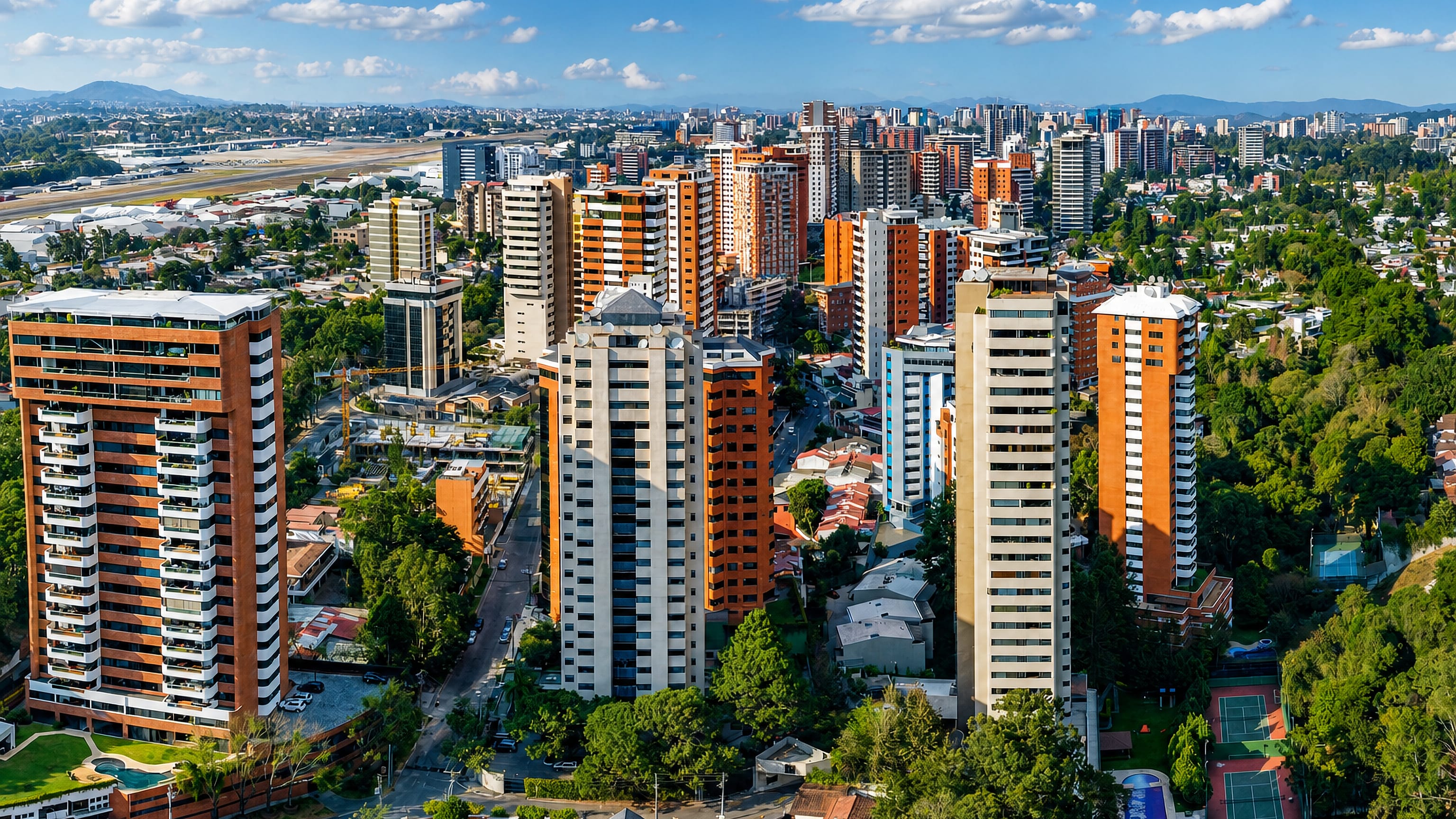 Aerial view over Guatemala City's high-rise residential zones with the La Aurora airport runway beyond