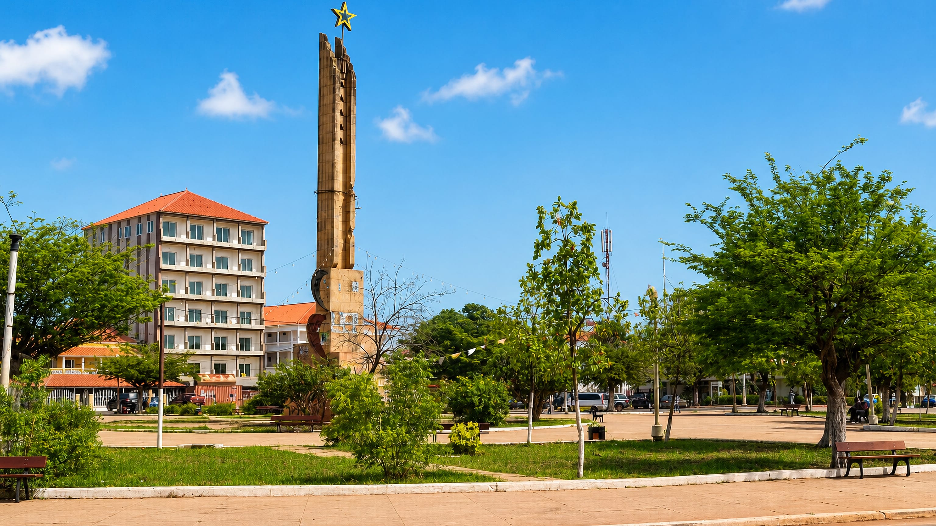 Star-topped concrete monument rising over a leafy central square in Bissau, Guinea-Bissau