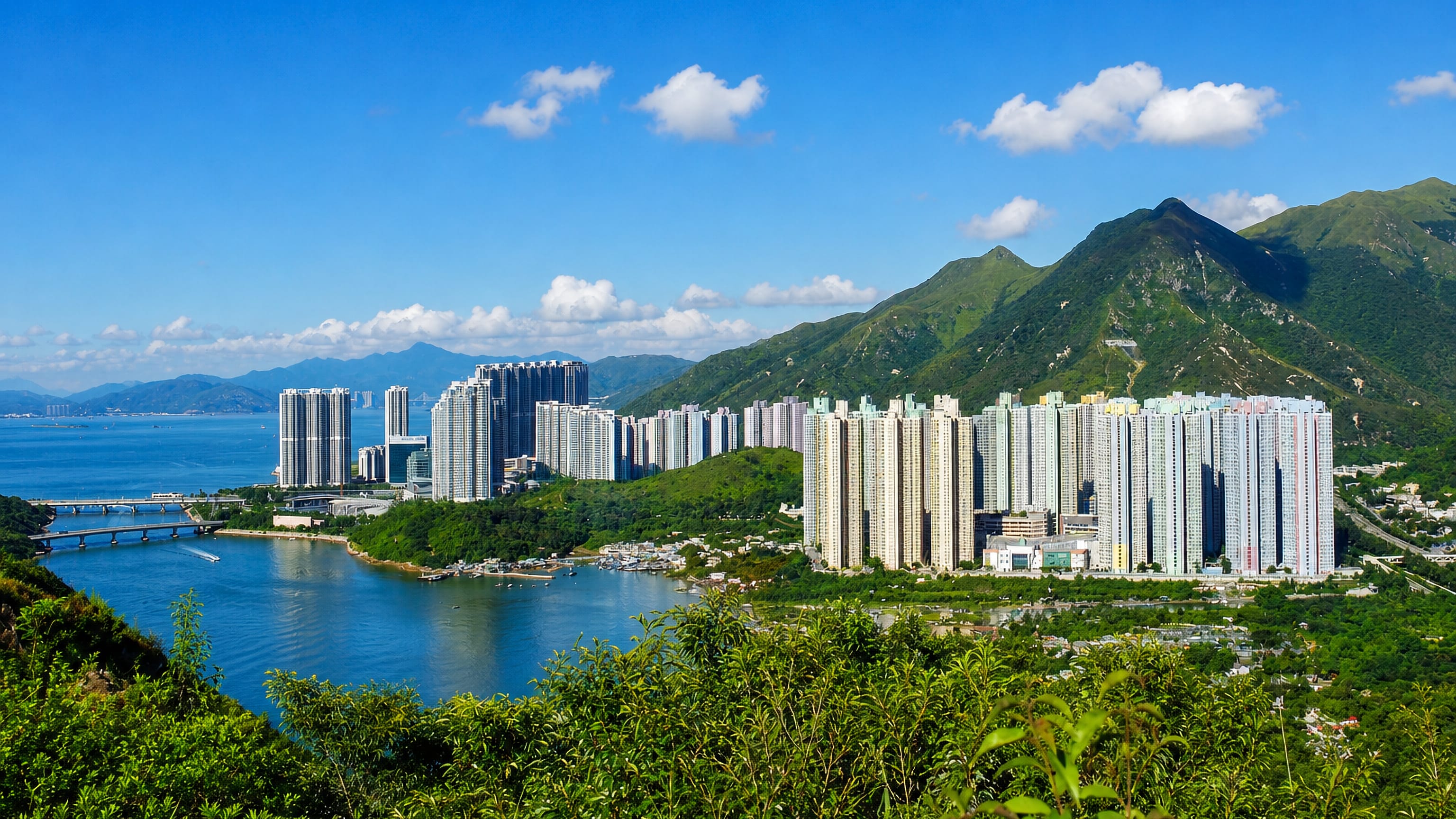 High-rise housing estates below green Lantau hills beside the bay at Tung Chung, Hong Kong.