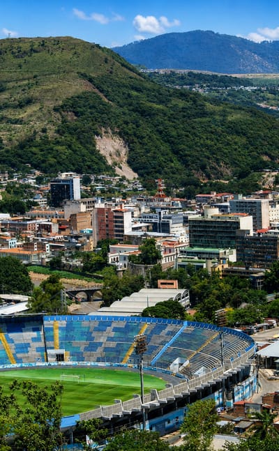 Tegucigalpa spread across a mountain valley with the Estadio Nacional stadium in the foreground.