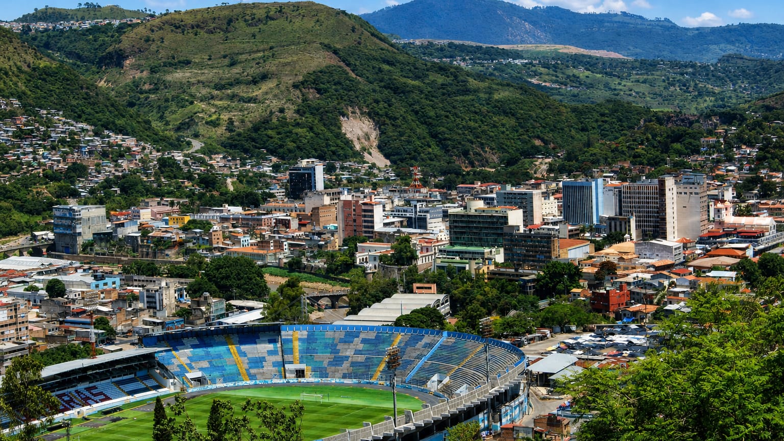 Tegucigalpa spread across a mountain valley with the Estadio Nacional stadium in the foreground.