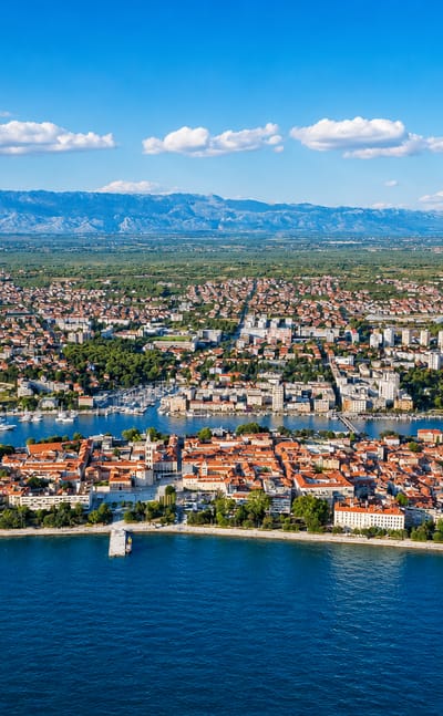 Aerial of Zadar's old town peninsula with red roofs, marina and the Adriatic backed by the Velebit mountains, Croatia