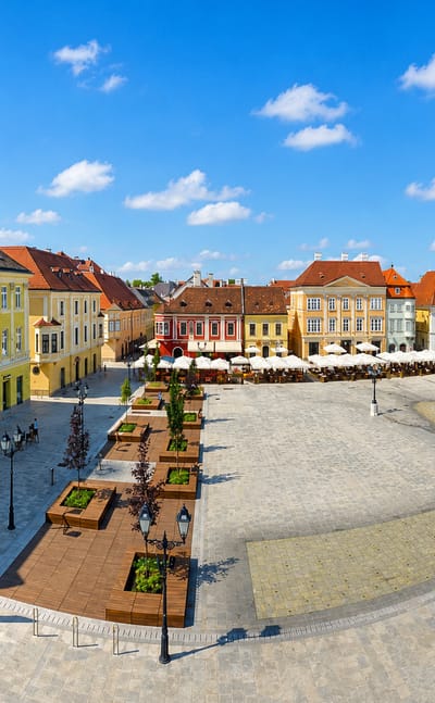 Gyor's Szechenyi Square with colorful baroque facades, cafe terraces and the Mary Column.
