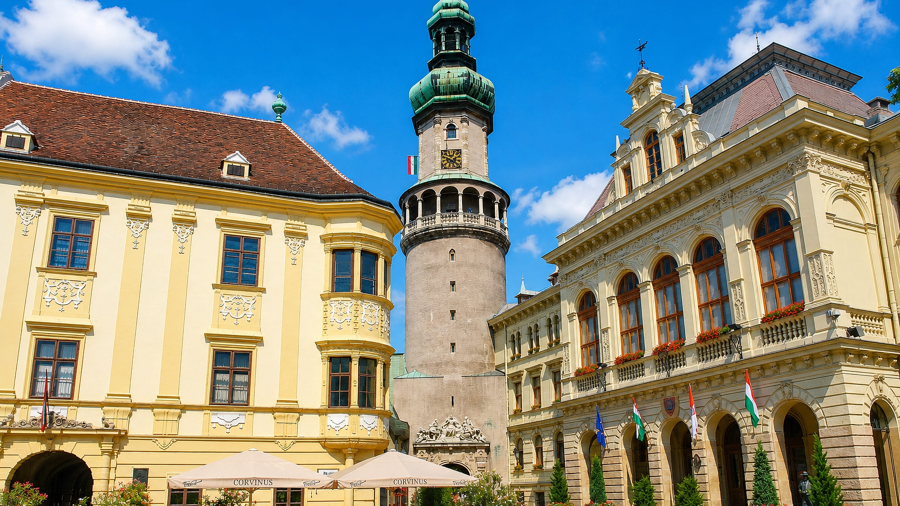 Sopron's main square in Hungary with the baroque Firewatch Tower rising between pastel town hall facades.