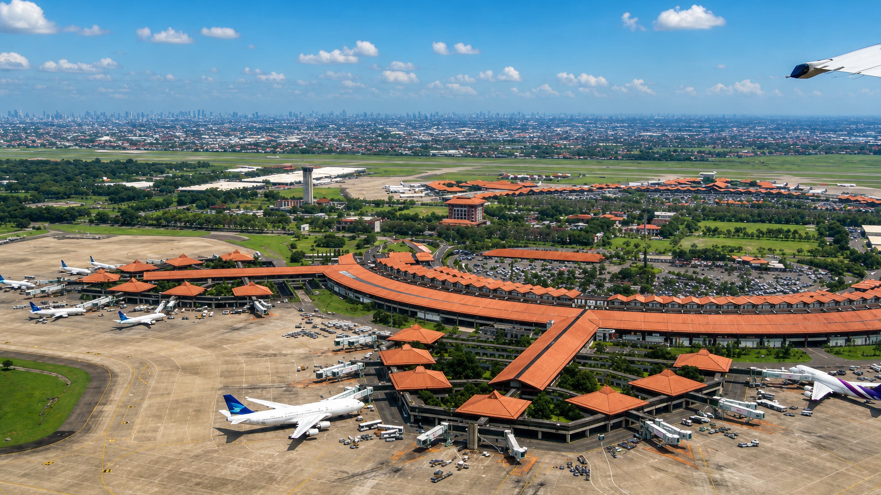 Aerial view of Soekarno-Hatta airport's terracotta-roofed terminals and apron in Tangerang, Indonesia.