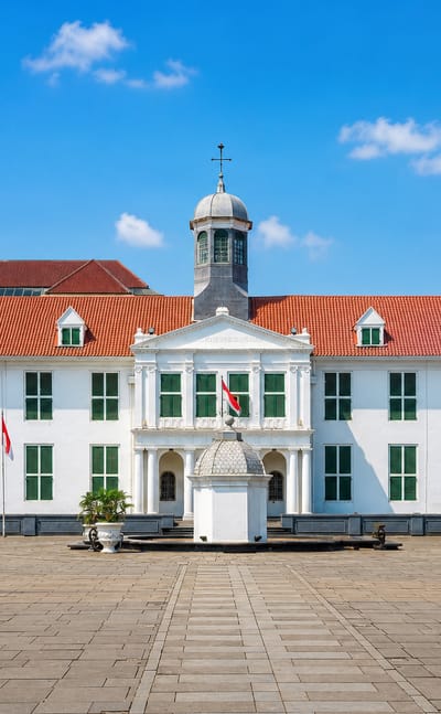 The white Dutch-colonial Jakarta History Museum with red-tiled roof and cupola on Fatahillah Square in Kota Tua, Jakarta.