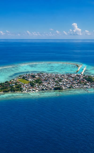 Aerial view of a small reef island town ringed by turquoise shallows in the Thousand Islands, Jakarta