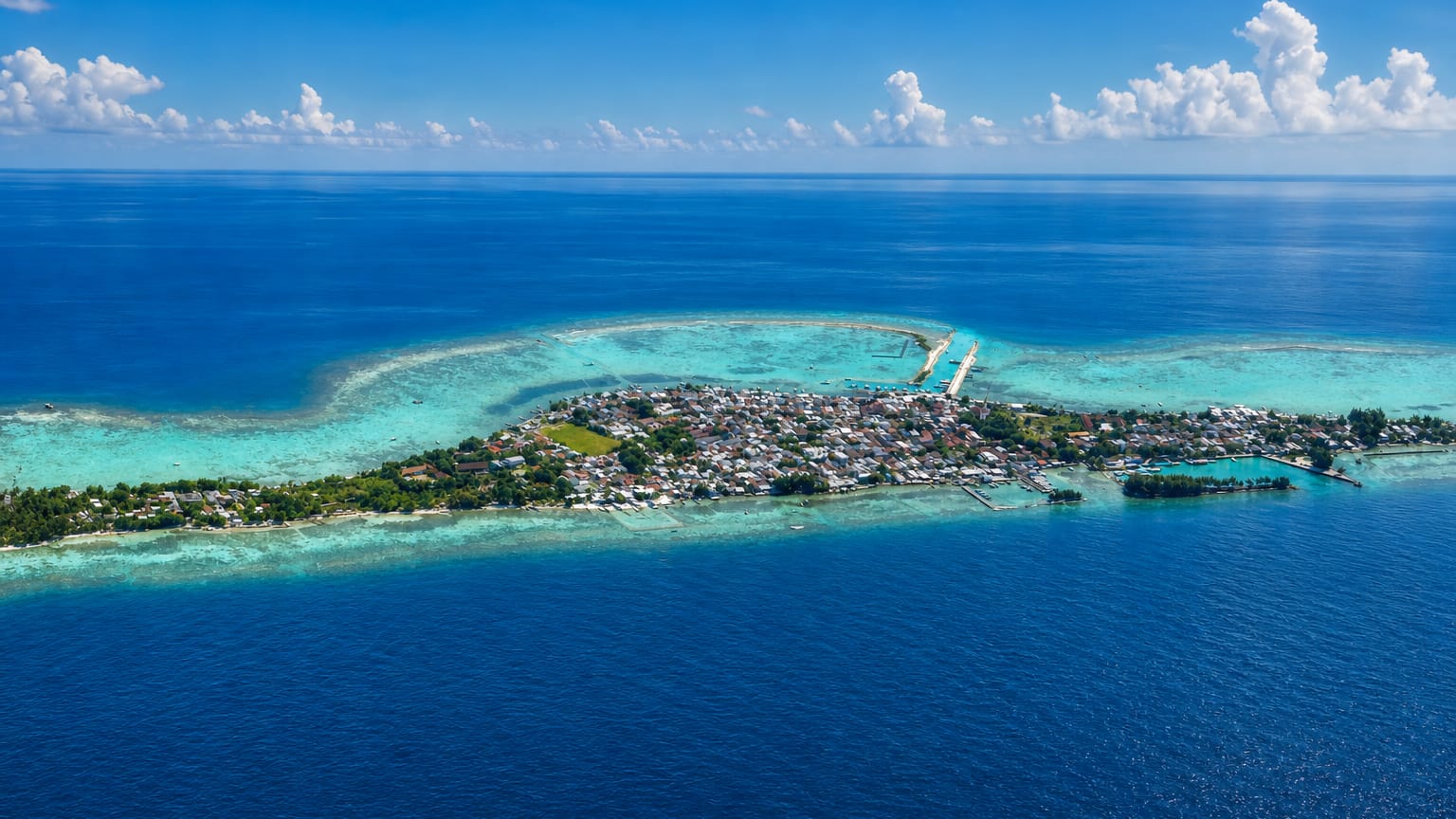 Aerial view of a small reef island town ringed by turquoise shallows in the Thousand Islands, Jakarta