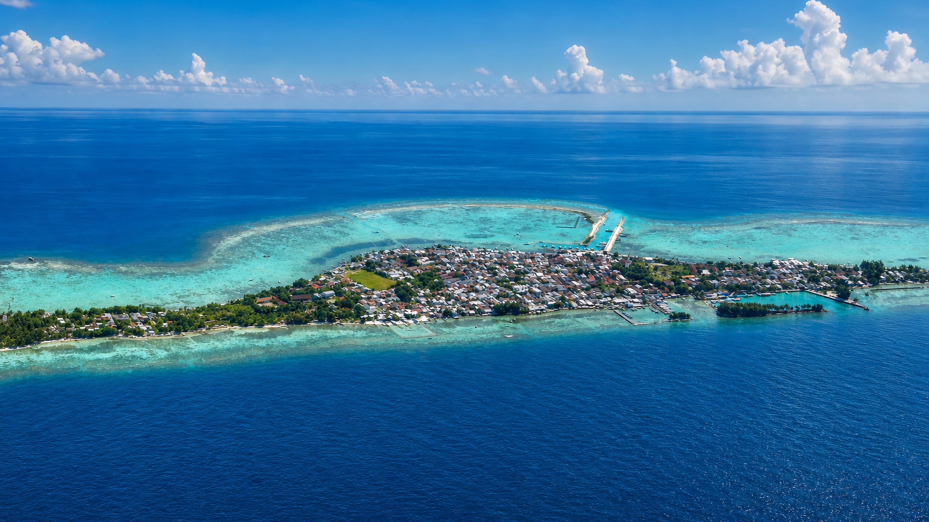 Aerial view of a small reef island town ringed by turquoise shallows in the Thousand Islands, Jakarta