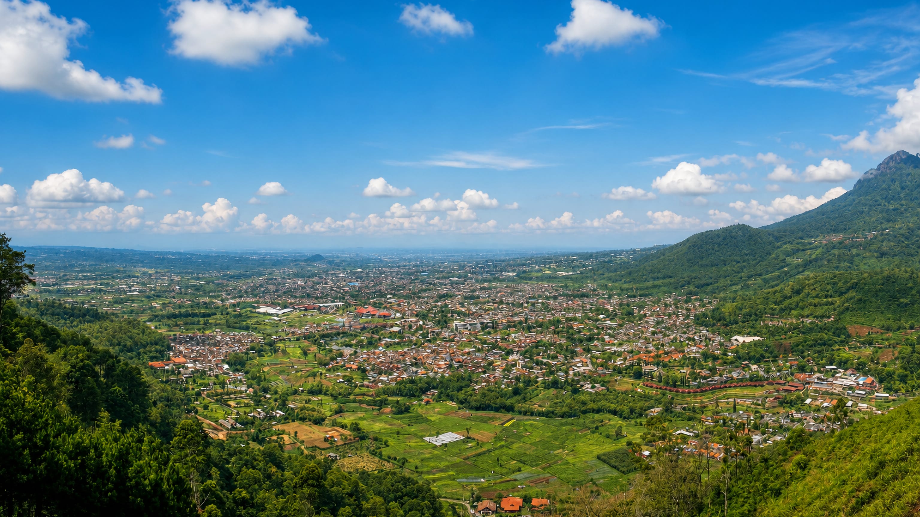 Panorama over Batu in East Java, its dense red-roofed houses and farm plots filling a mountain-ringed valley.
