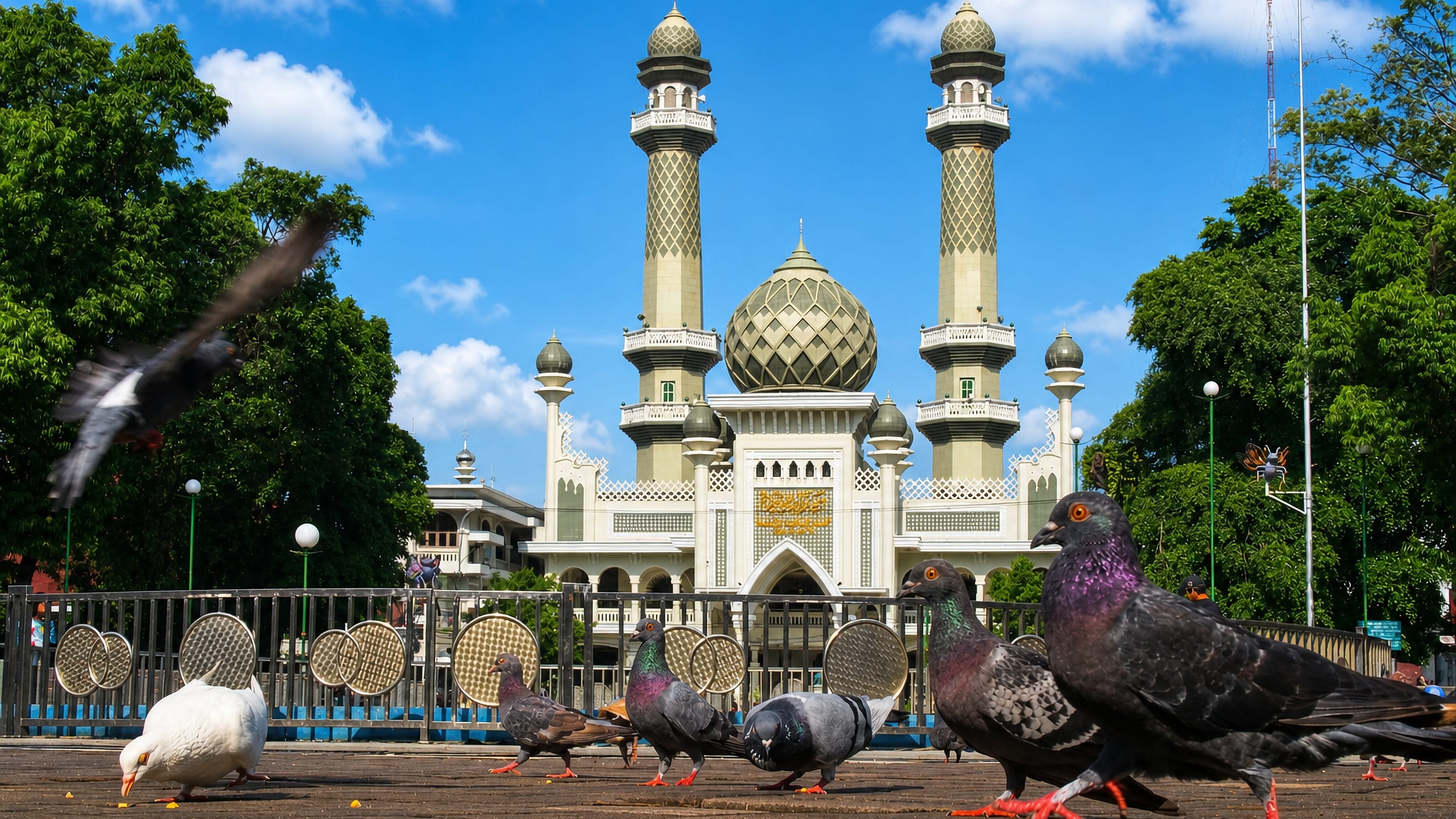 Pigeons on the plaza before the twin minarets and dome of Masjid Jami' on Malang's main square.