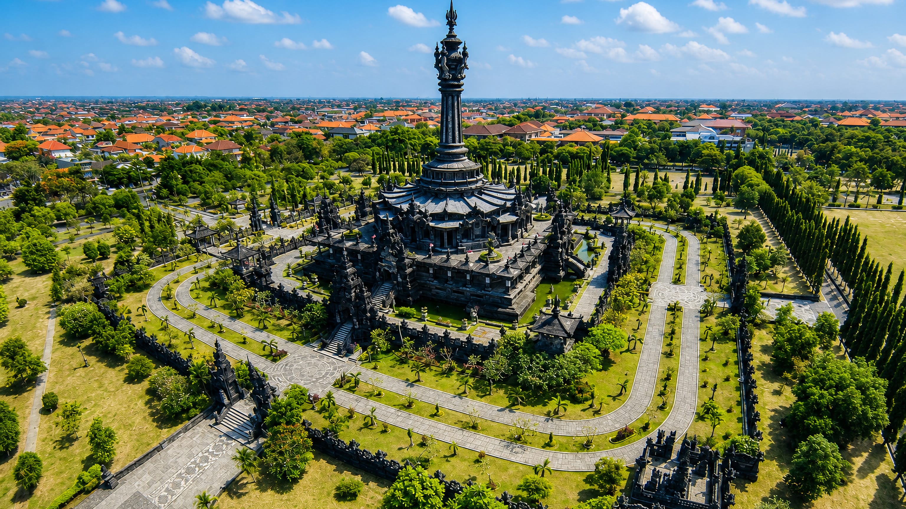 Aerial view of the Bajra Sandhi Monument and its gardens in Renon, Denpasar, with Bali's tiled rooftops beyond.
