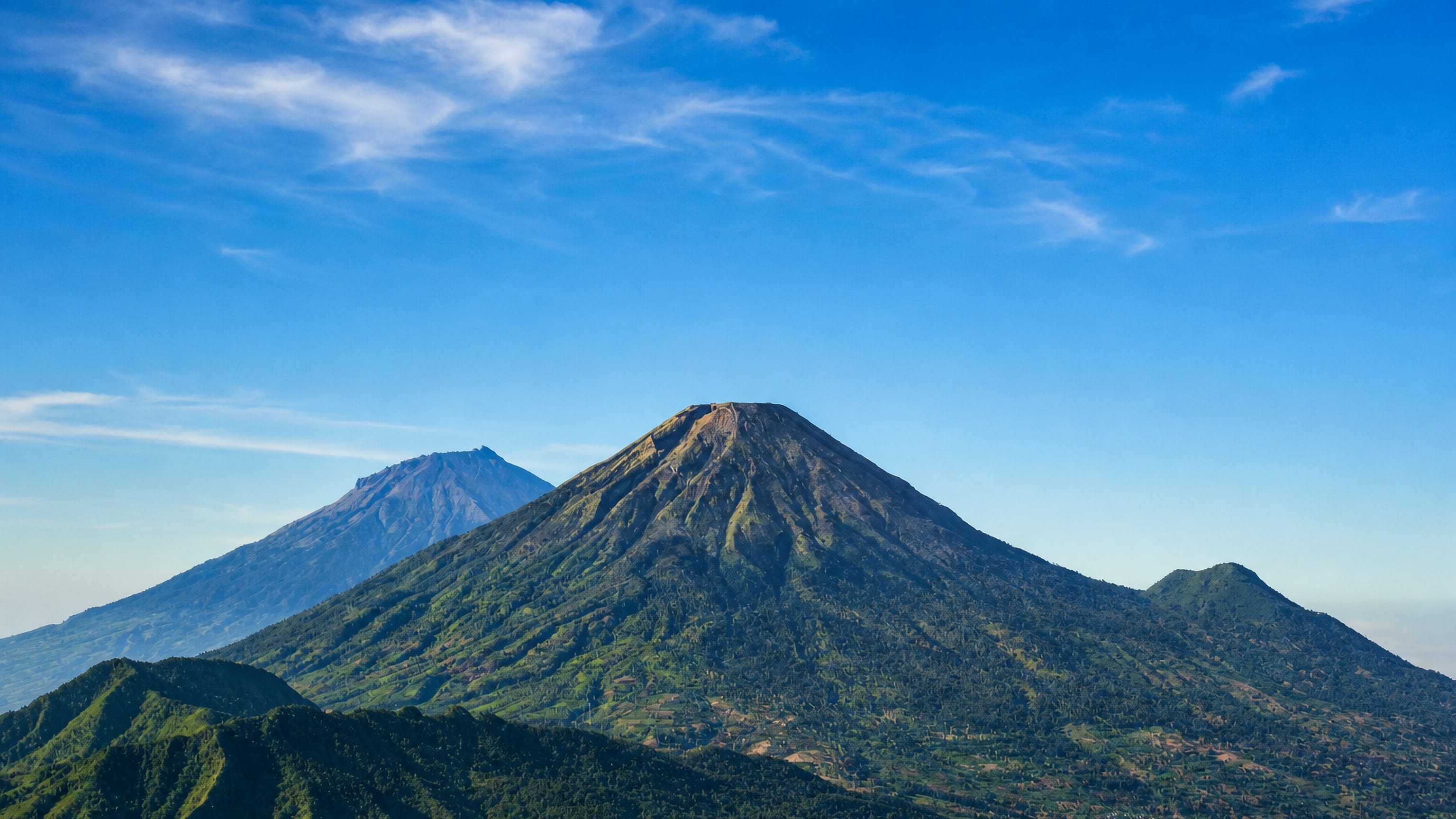The twin volcanic cones of Sindoro and Sumbing rising over the green highlands above Wonosobo, Central Java.