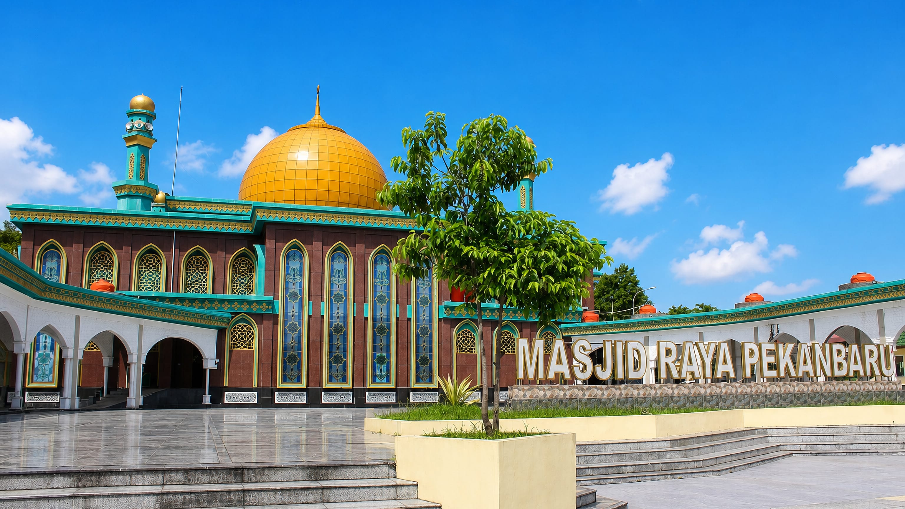 The golden dome and lettered sign of Masjid Raya Pekanbaru under a clear sky in Riau, Indonesia.