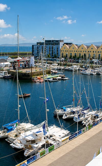 Galway's harbour marina filled with yachts beside yellow gabled dock warehouses during a sailing event
